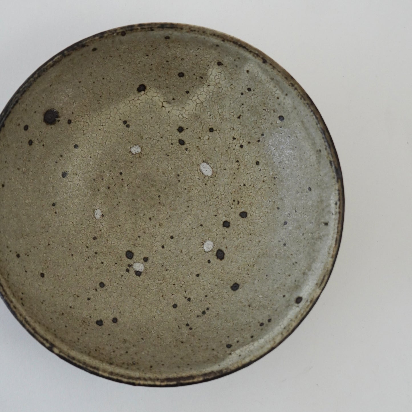 Speckled ceramic plate on a white background. Handmade ceramic plate by Japanese artist at Gallery tete Hong Kong.