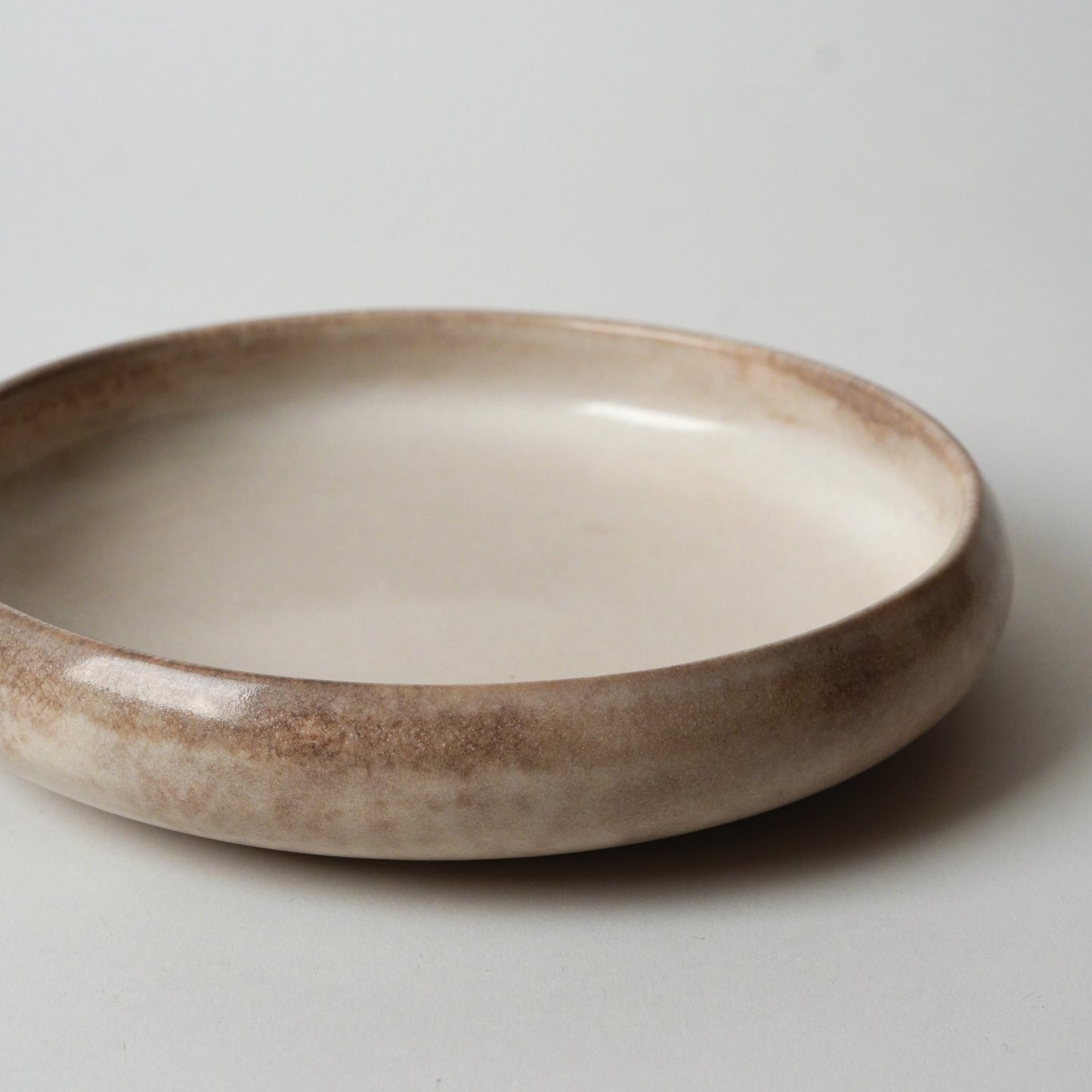 Ceramic bowl with a brown and beige gradient on a light gray background