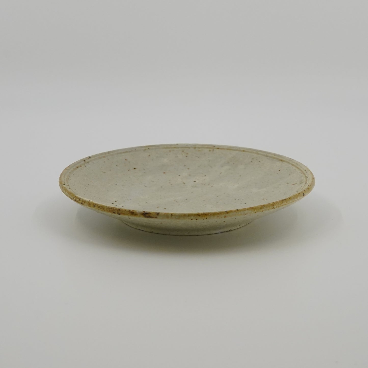 Ceramic plate with a speckled glaze on a white background
