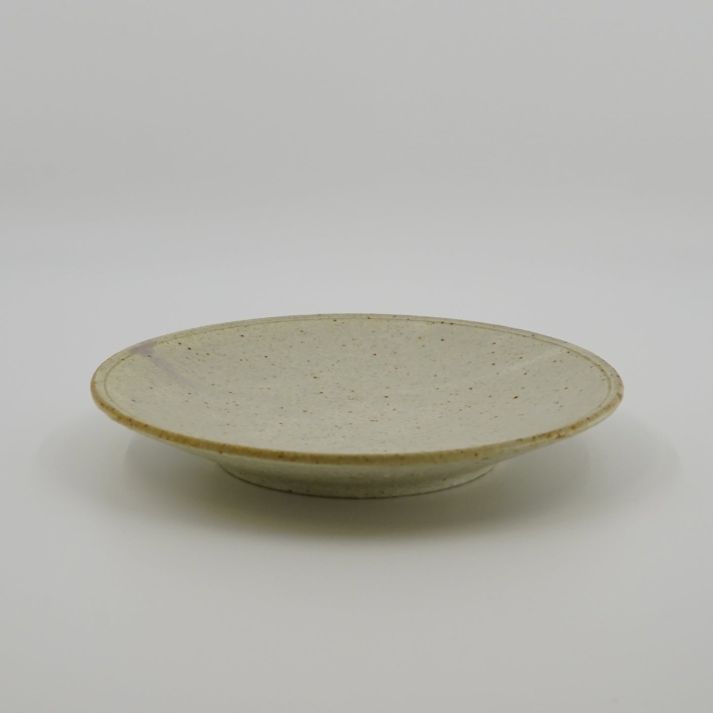 Ceramic plate with speckled glaze on a white background