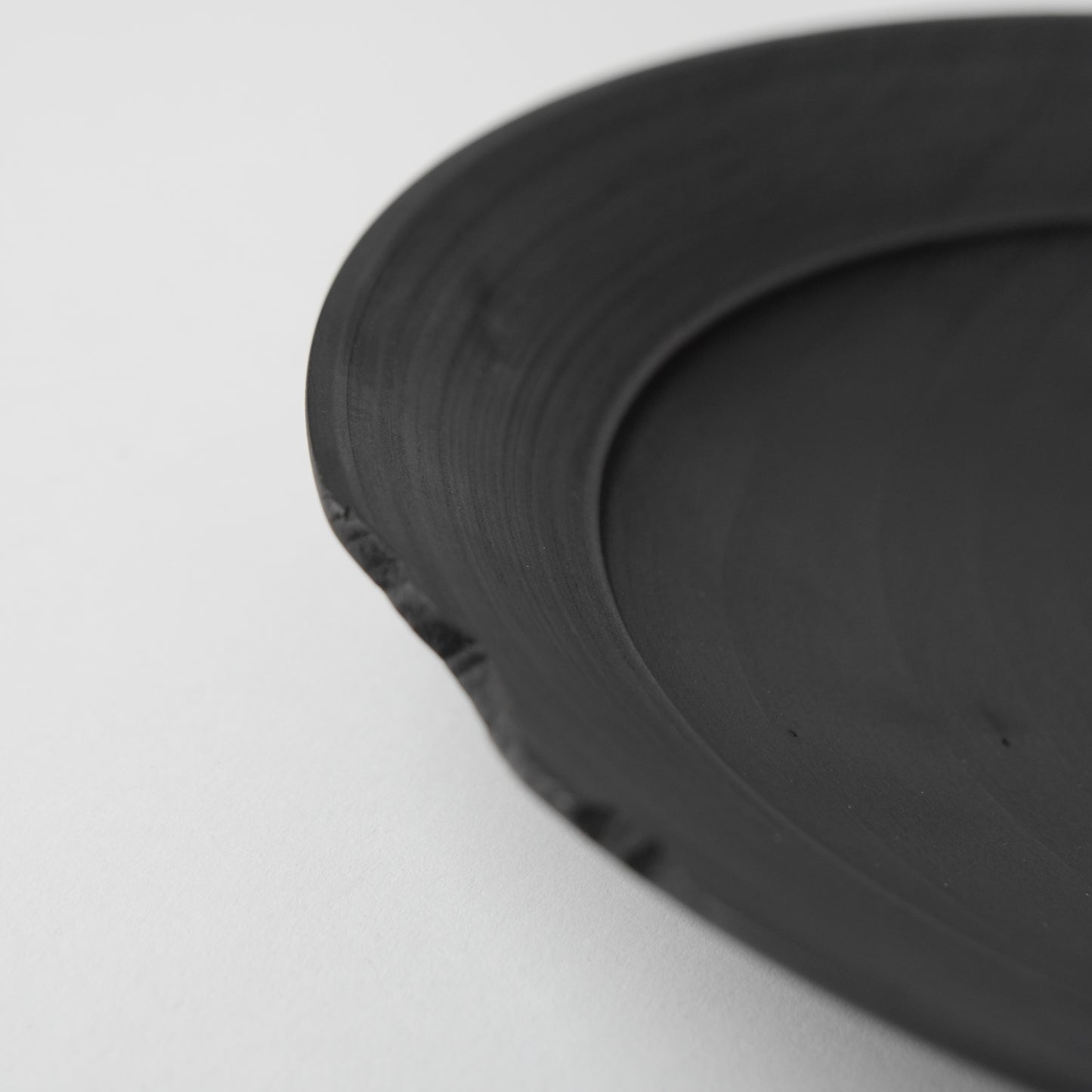 Close-up of a black wooden plate on a light gray background