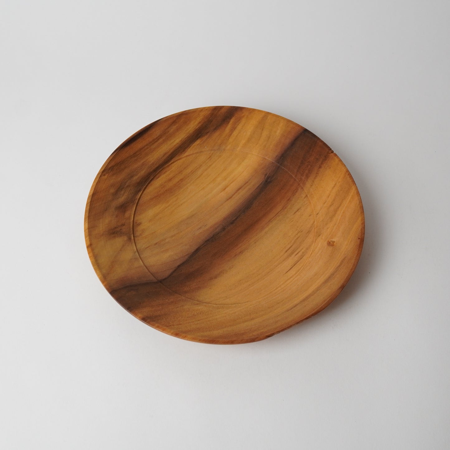 Wooden plate with a natural grain pattern on a light gray background
