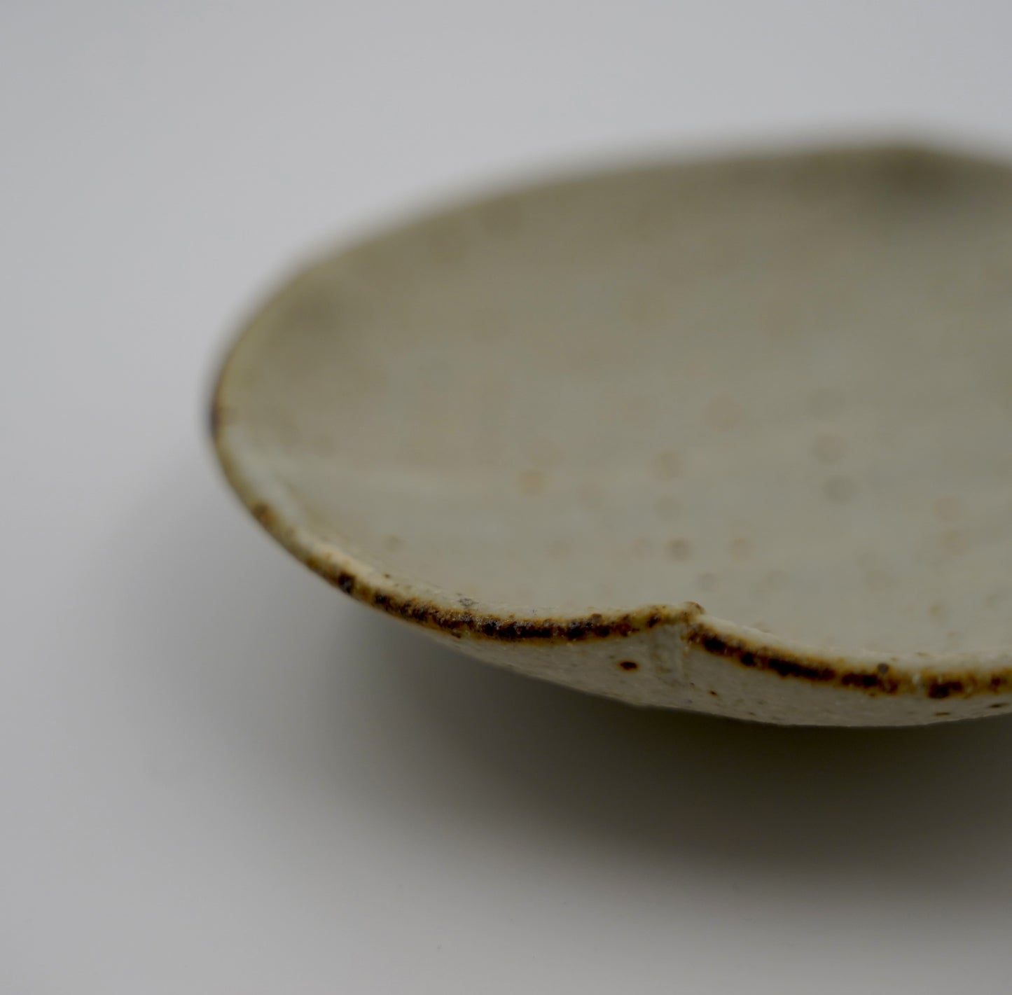 Close-up of a ceramic plate with a brown rim on a white background