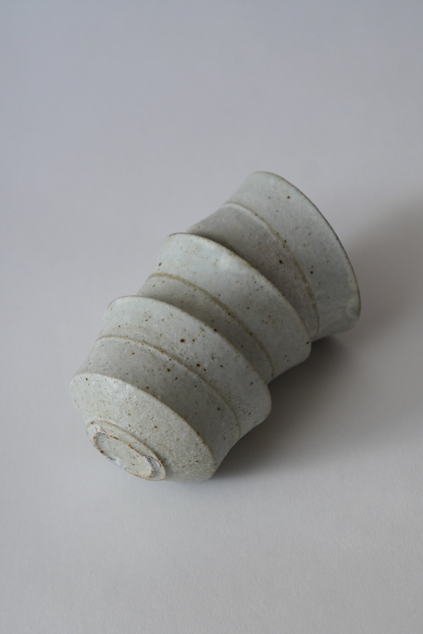 Cylindrical ceramic object on a plain background. Handmade ceramic cup by Japanese artist at Gallery tete Hong Kong.