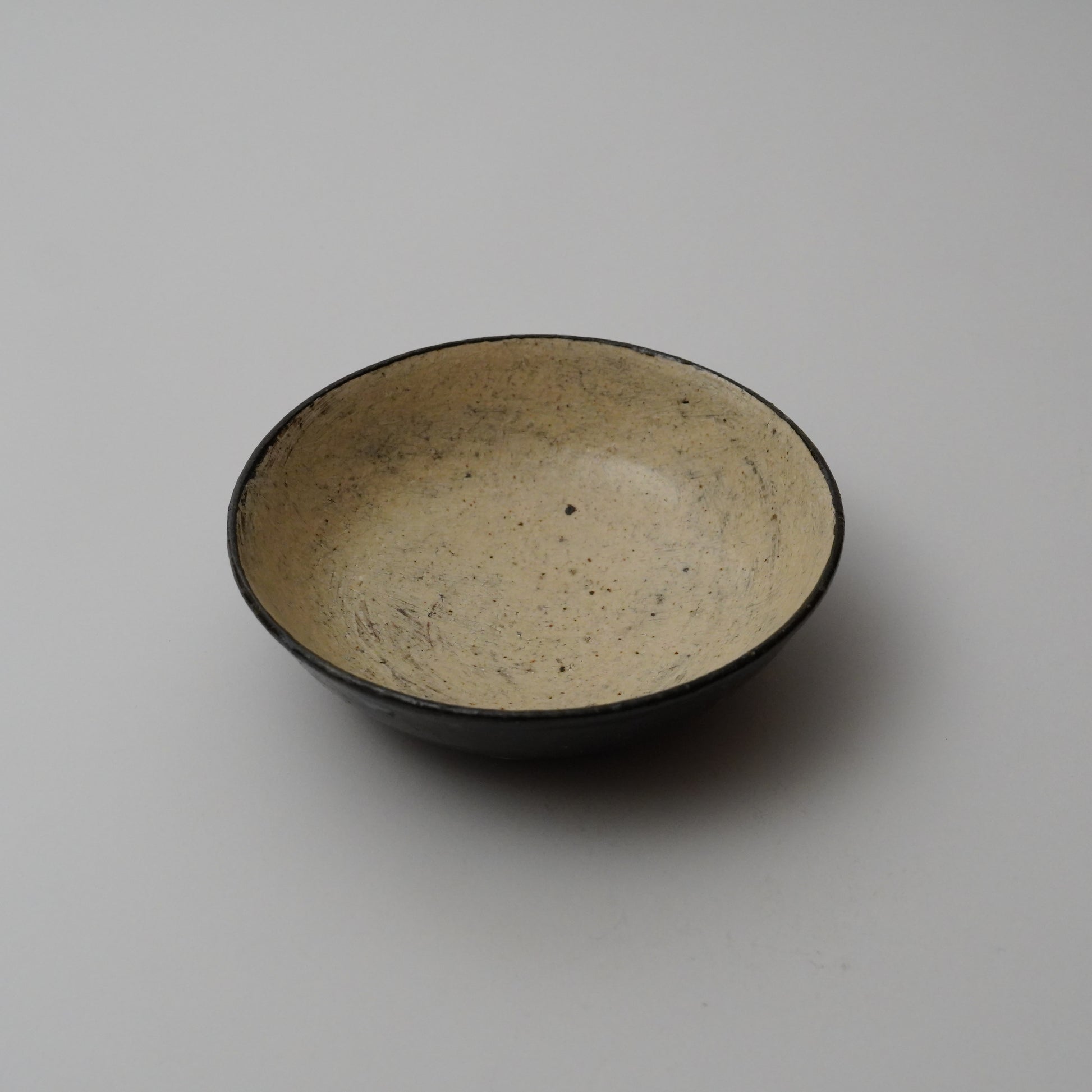 Ceramic bowl with speckled glaze on a plain background