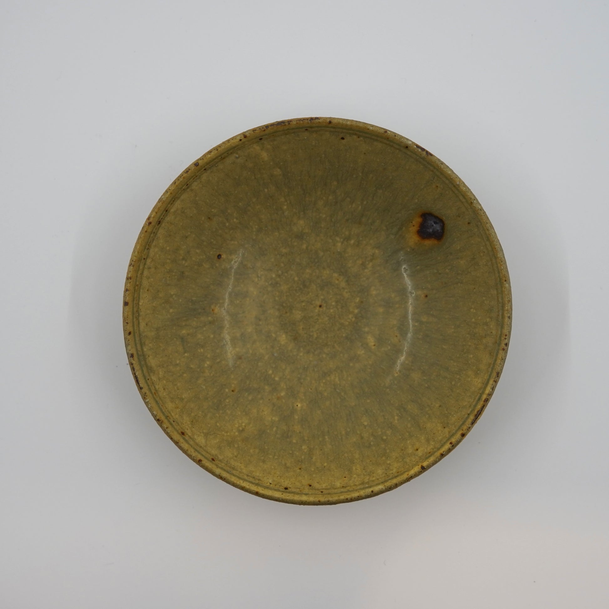 Round ceramic dish with a brownish-green glaze on a white background