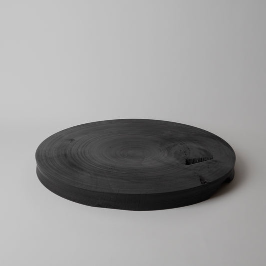 Round black wooden tray on a light gray background