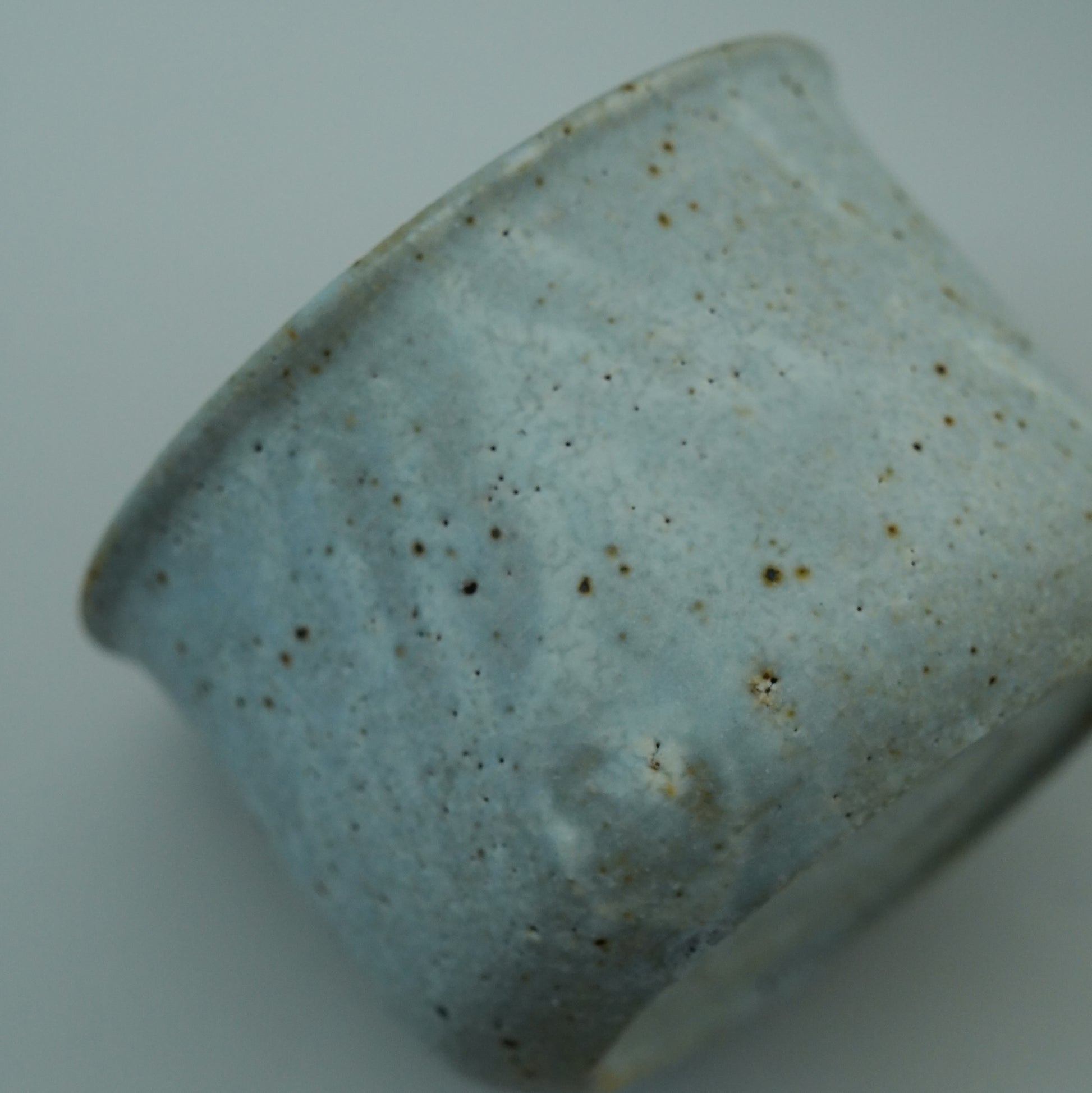 Close-up of a ceramic cup with speckled glaze on a white background. Handmade ceramic cup by Japanese artist at Gallery tete Hong Kong.