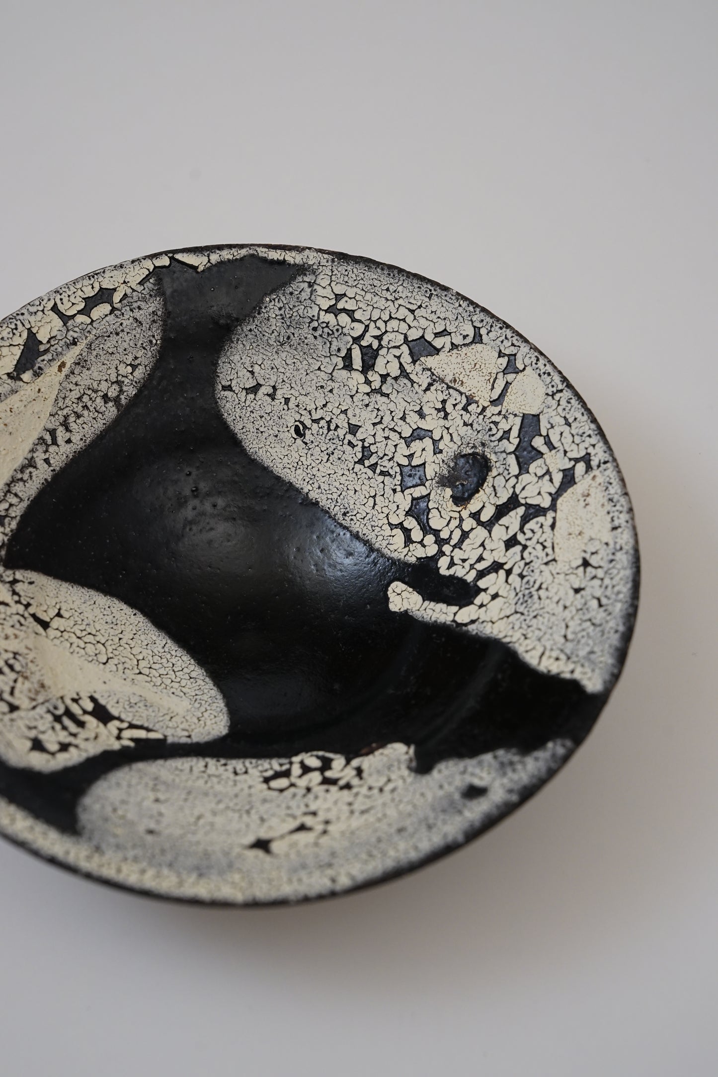 Ceramic bowl with black and white speckled pattern on a white background