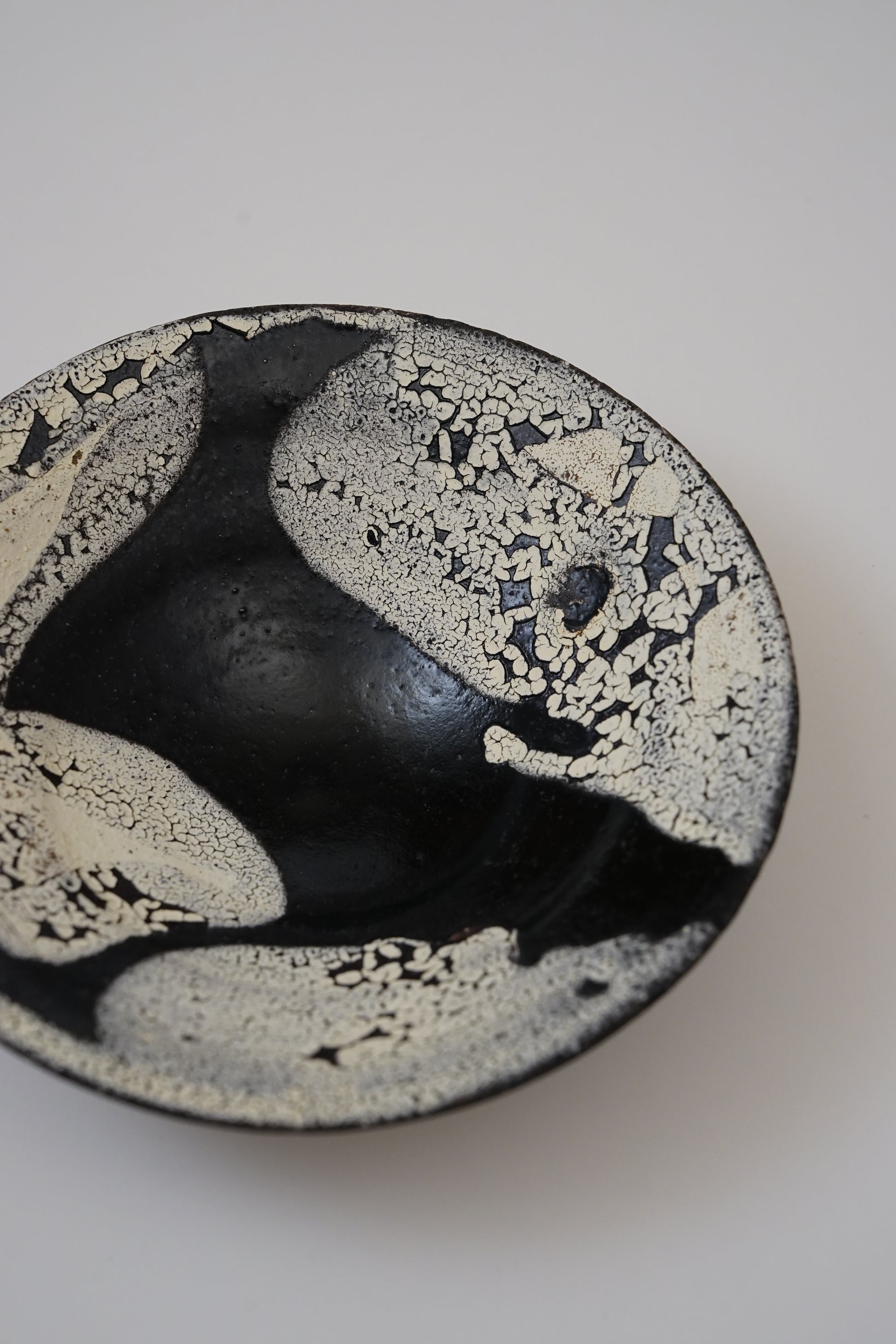 Ceramic bowl with black and white speckled pattern on a white background
