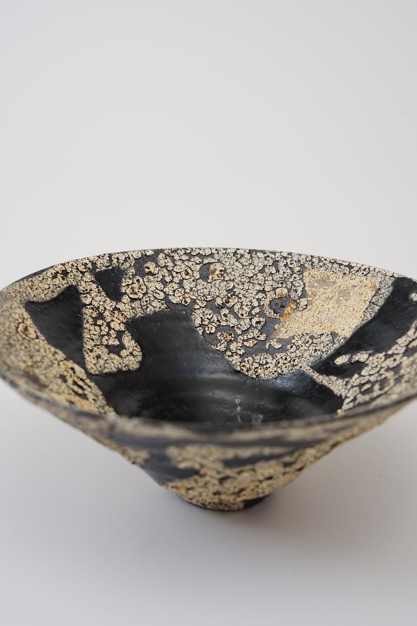 A handmade ceramic bowl with a glossy black glaze and textured gold leaf patterns, photographed on a clean white background.