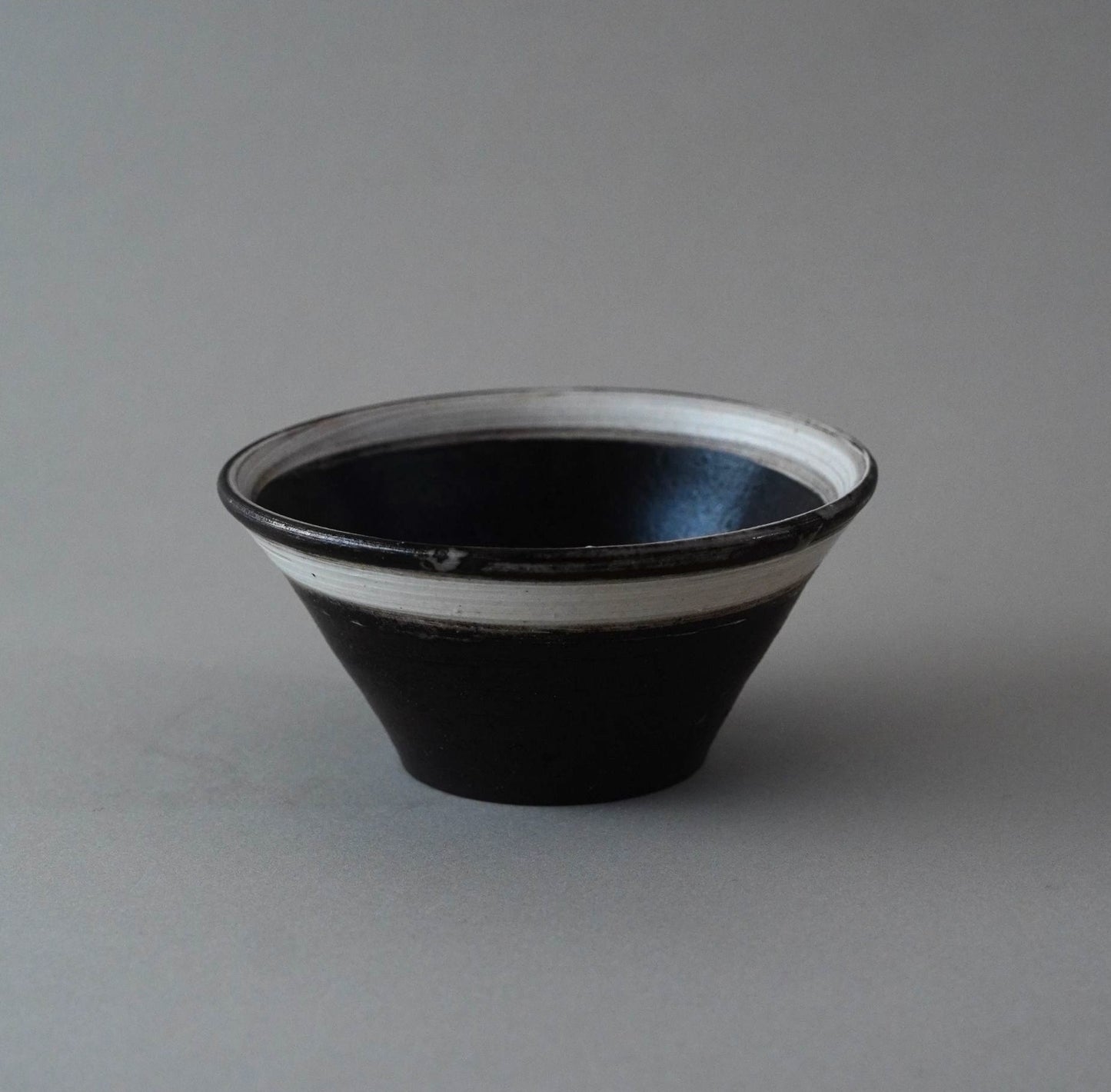 Black ceramic bowl with white interior on a gray background