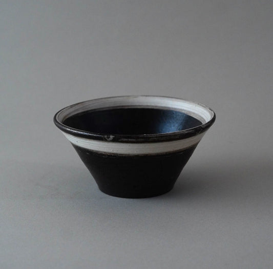 Black ceramic bowl with white interior on a gray background
