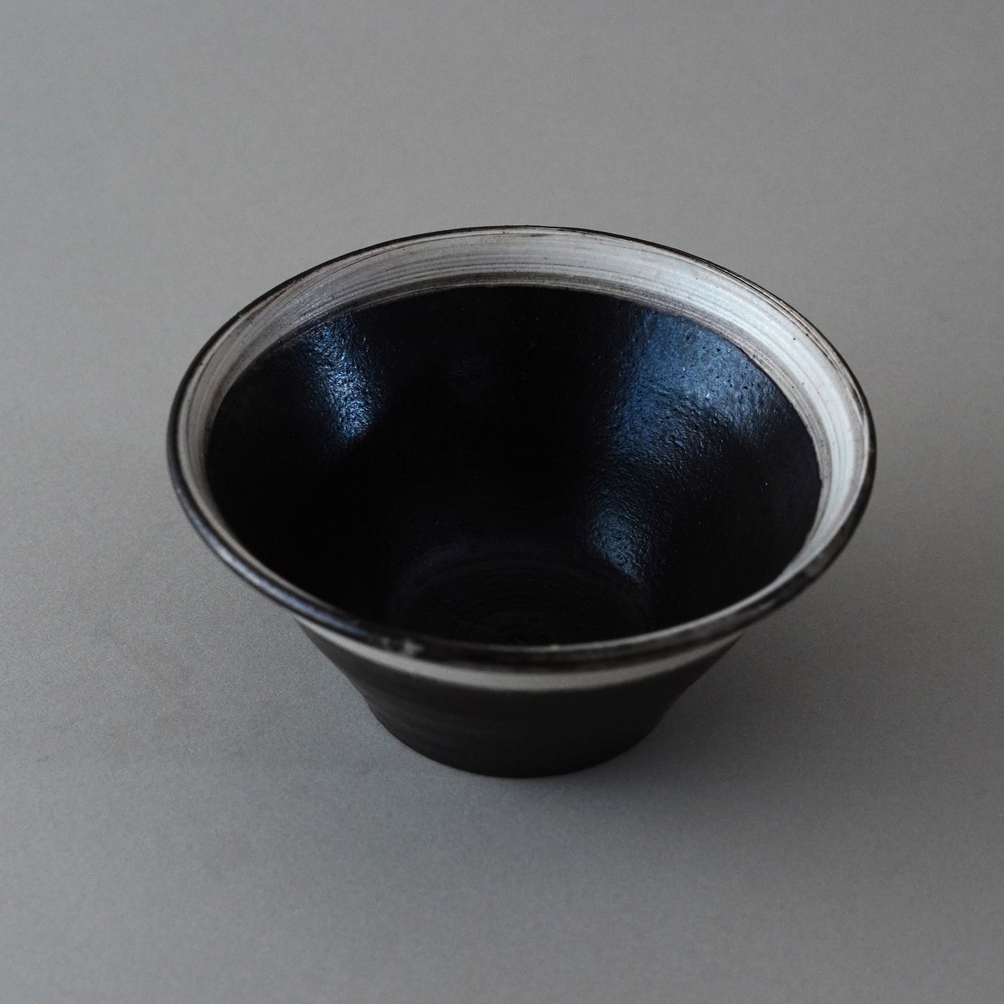 Black ceramic cup with white interior on a gray background