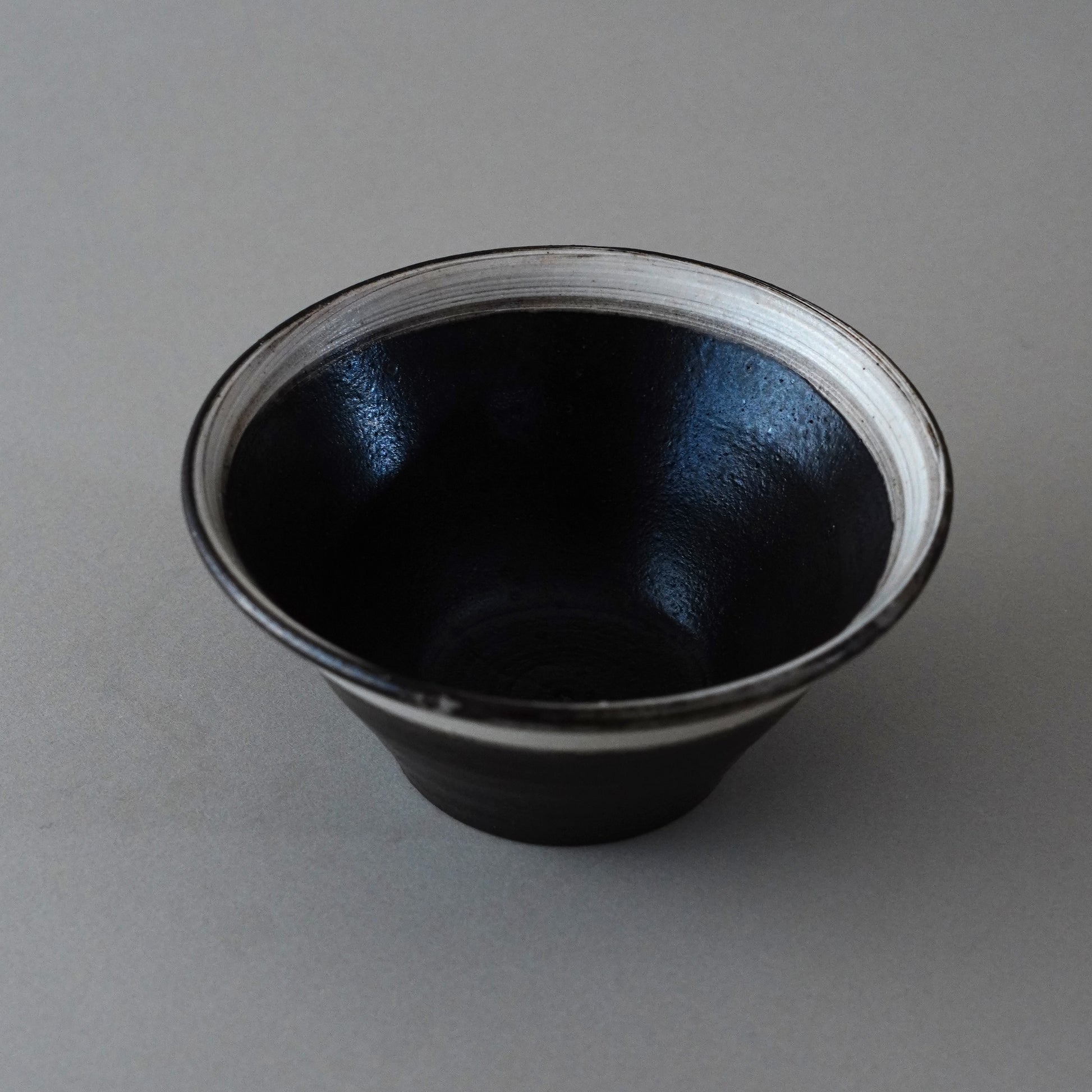 Black ceramic cup with white interior on a gray background