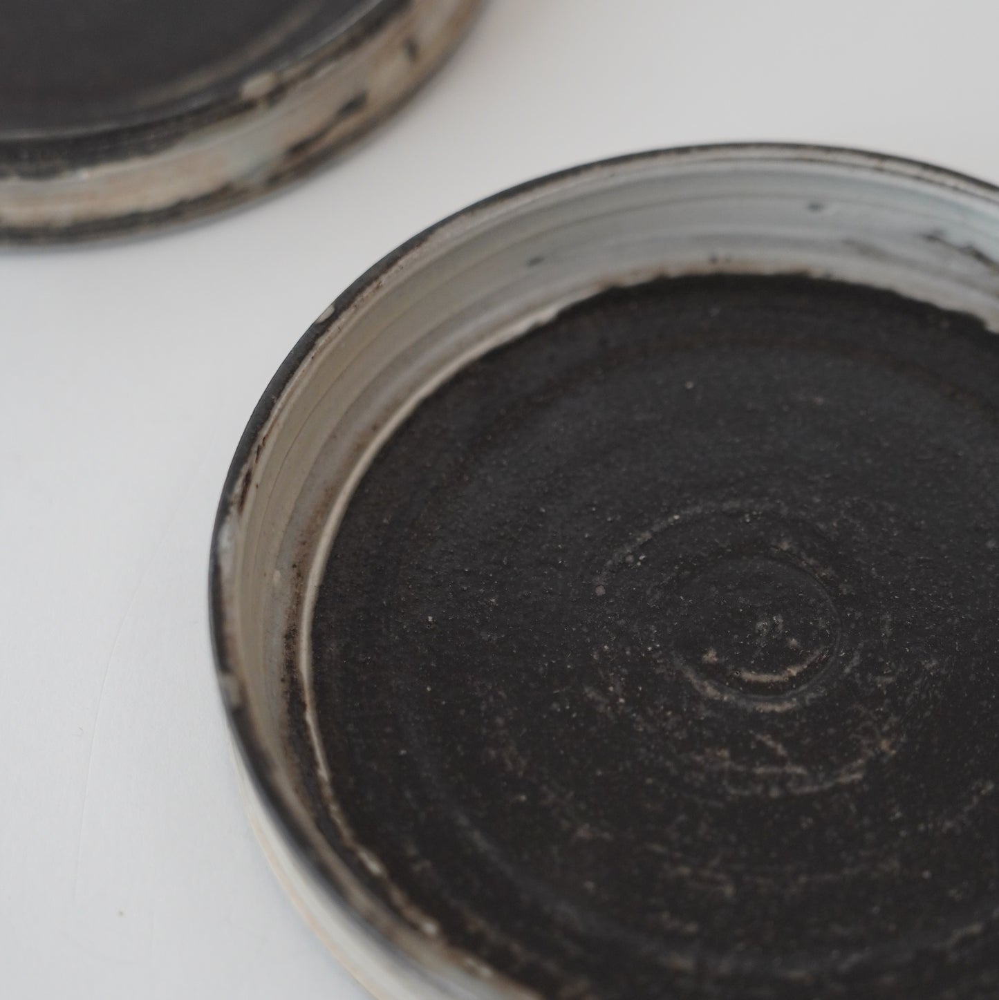 Close-up of a black ceramic pot with a textured surface on a white background. Handmade ceramic  plate by Japanese artist at Gallery tete Hong Kong.