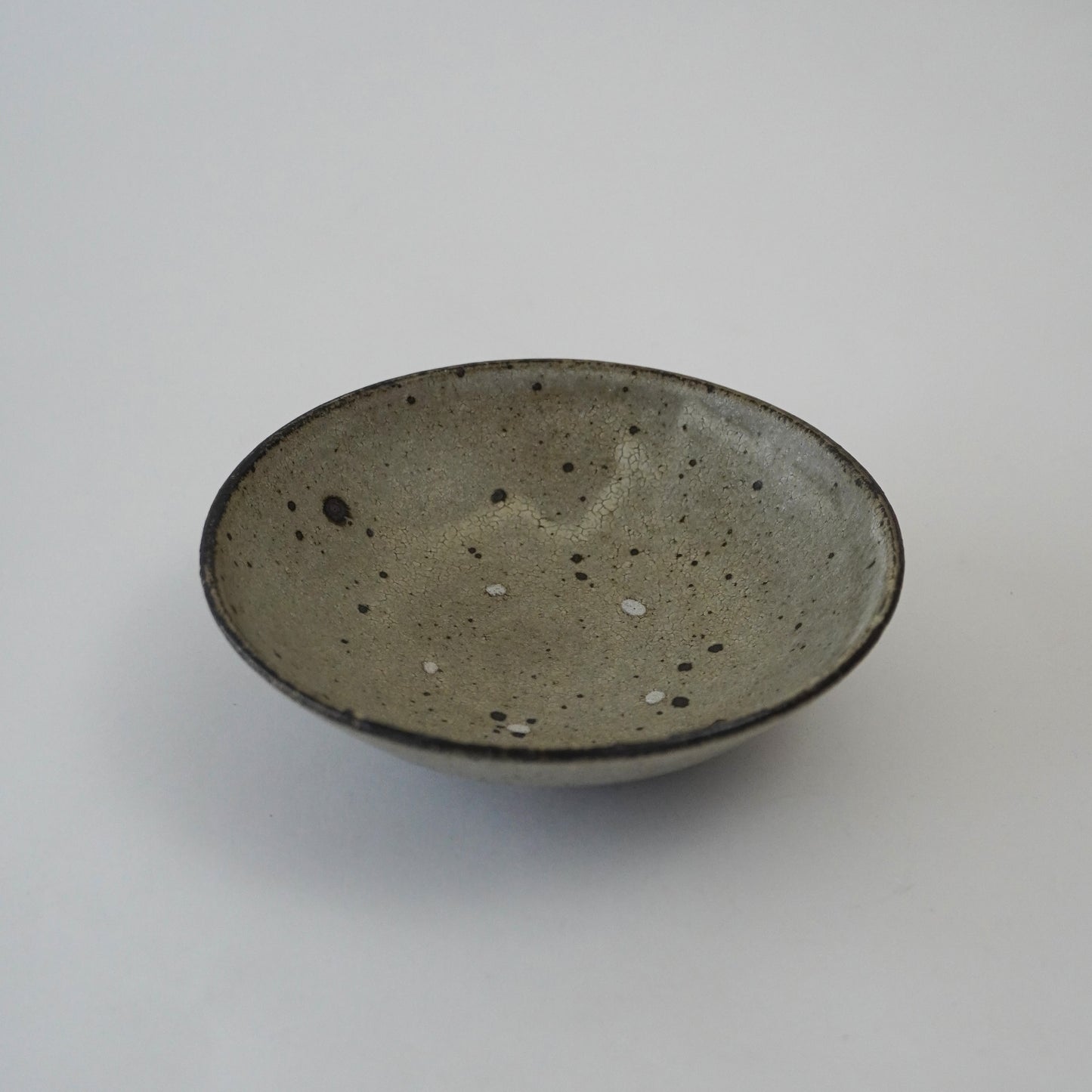Ceramic bowl with speckled glaze on a white background. Handmade ceramic  plate by Japanese artist at Gallery tete Hong Kong.