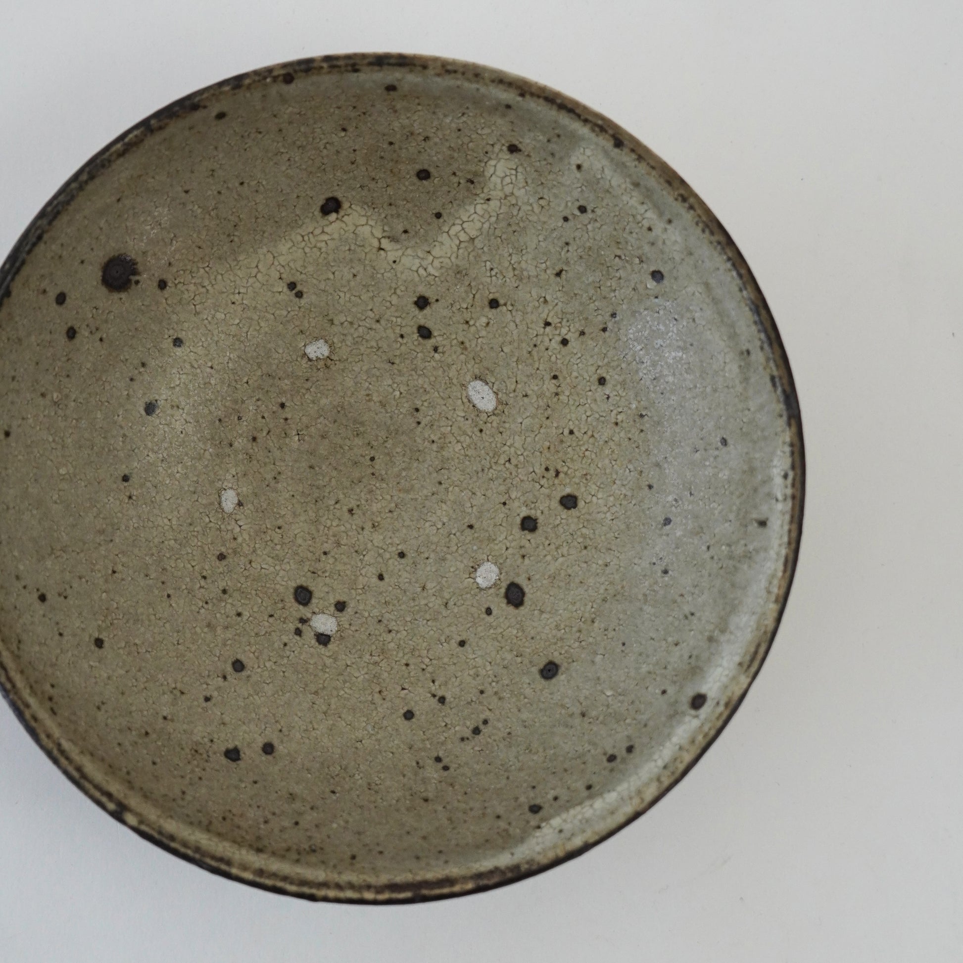 Speckled ceramic plate on a white background. Handmade ceramic  plate by Japanese artist at Gallery tete Hong Kong.