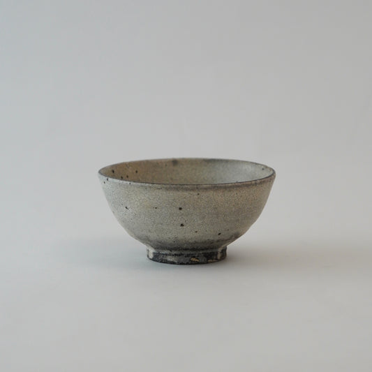 Small ceramic bowl with a speckled glaze on a light gray background