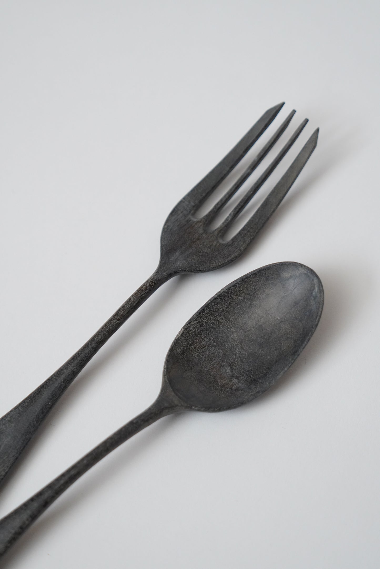 Black spoon and fork on a light gray background
