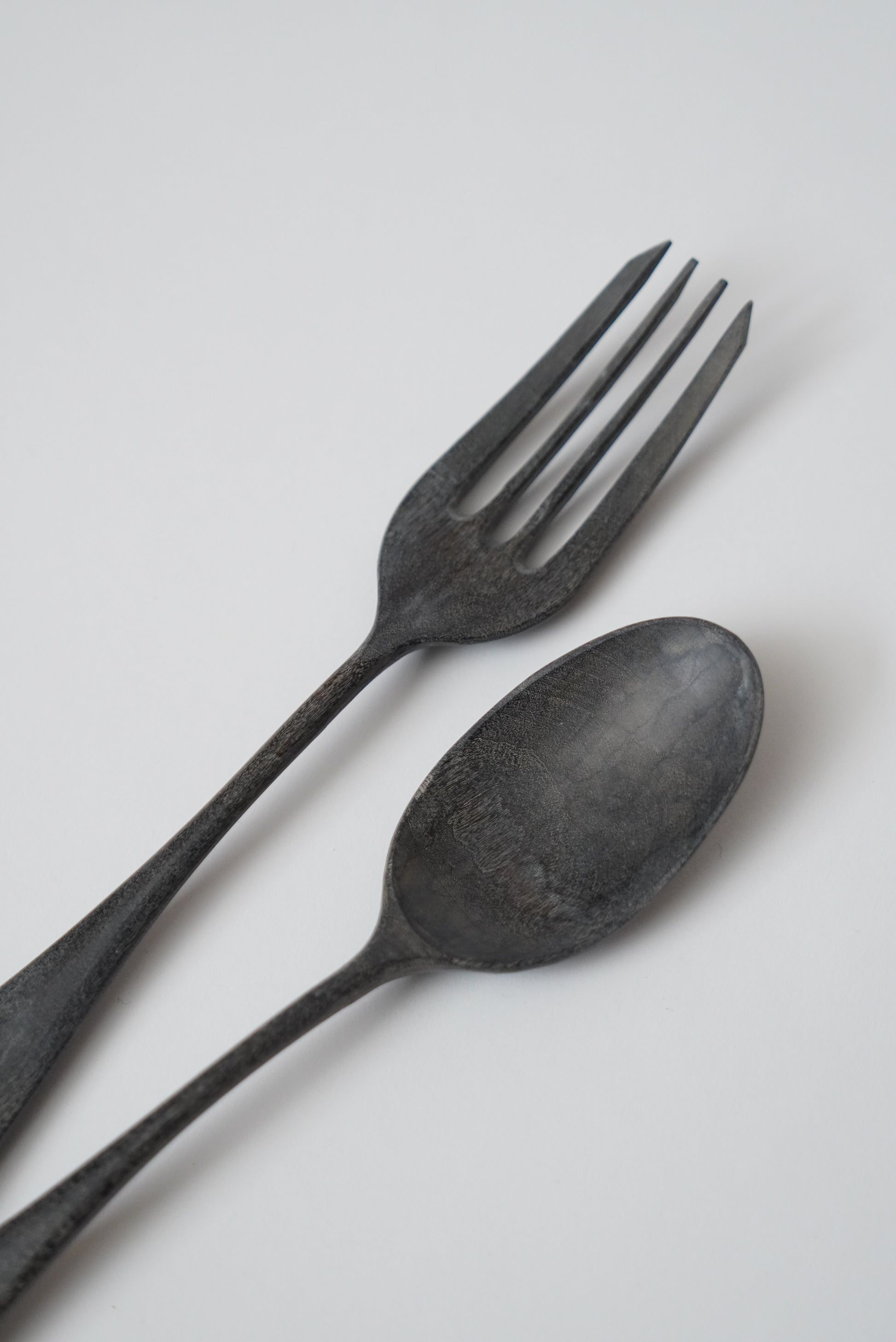 Black spoon and fork on a light gray background