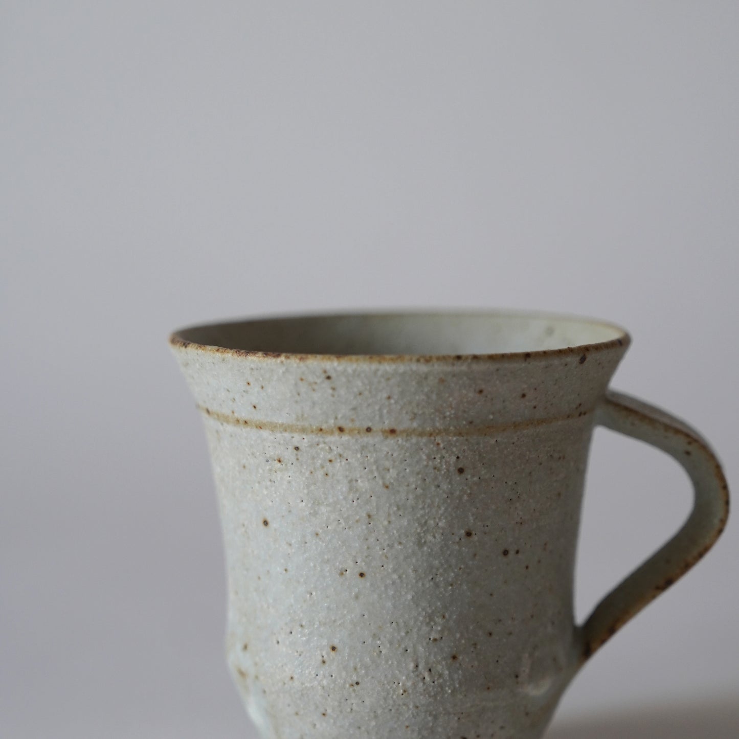 Ceramic mug with speckled texture on a plain background