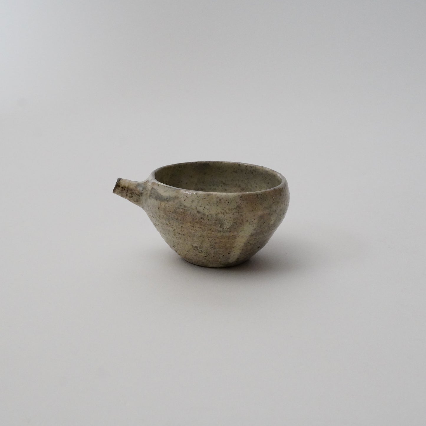 A gray ceramic pitcher with a textured finish on a white background.