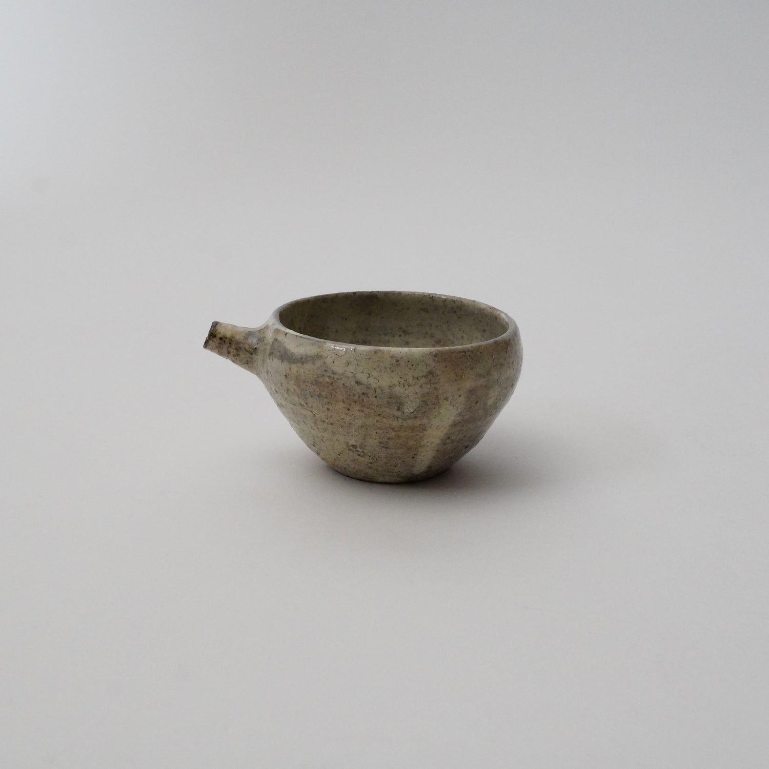 A gray ceramic pitcher with a textured finish on a white background.