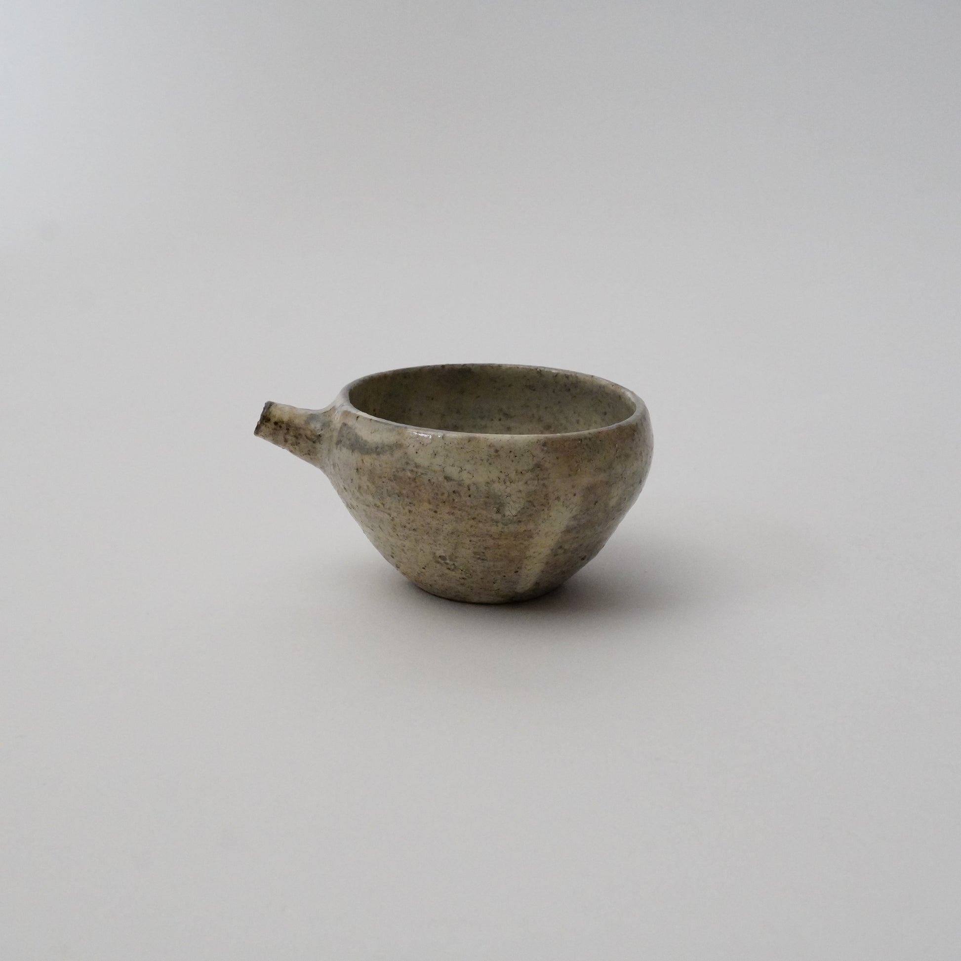 A gray ceramic pitcher with a textured finish on a white background.