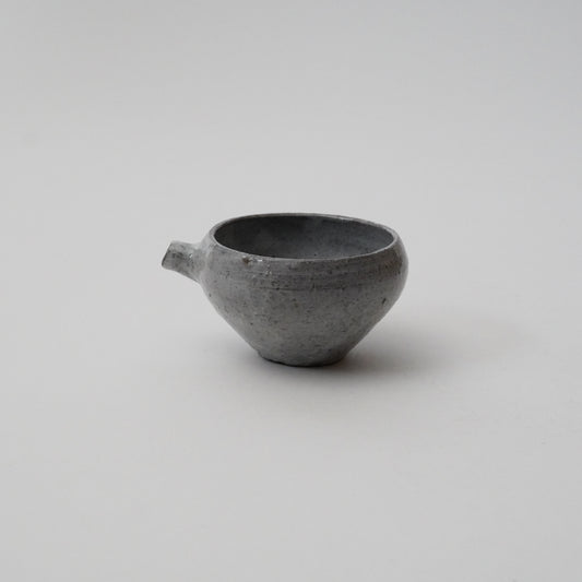 A gray ceramic pitcher with a round body and a spout on a white background.