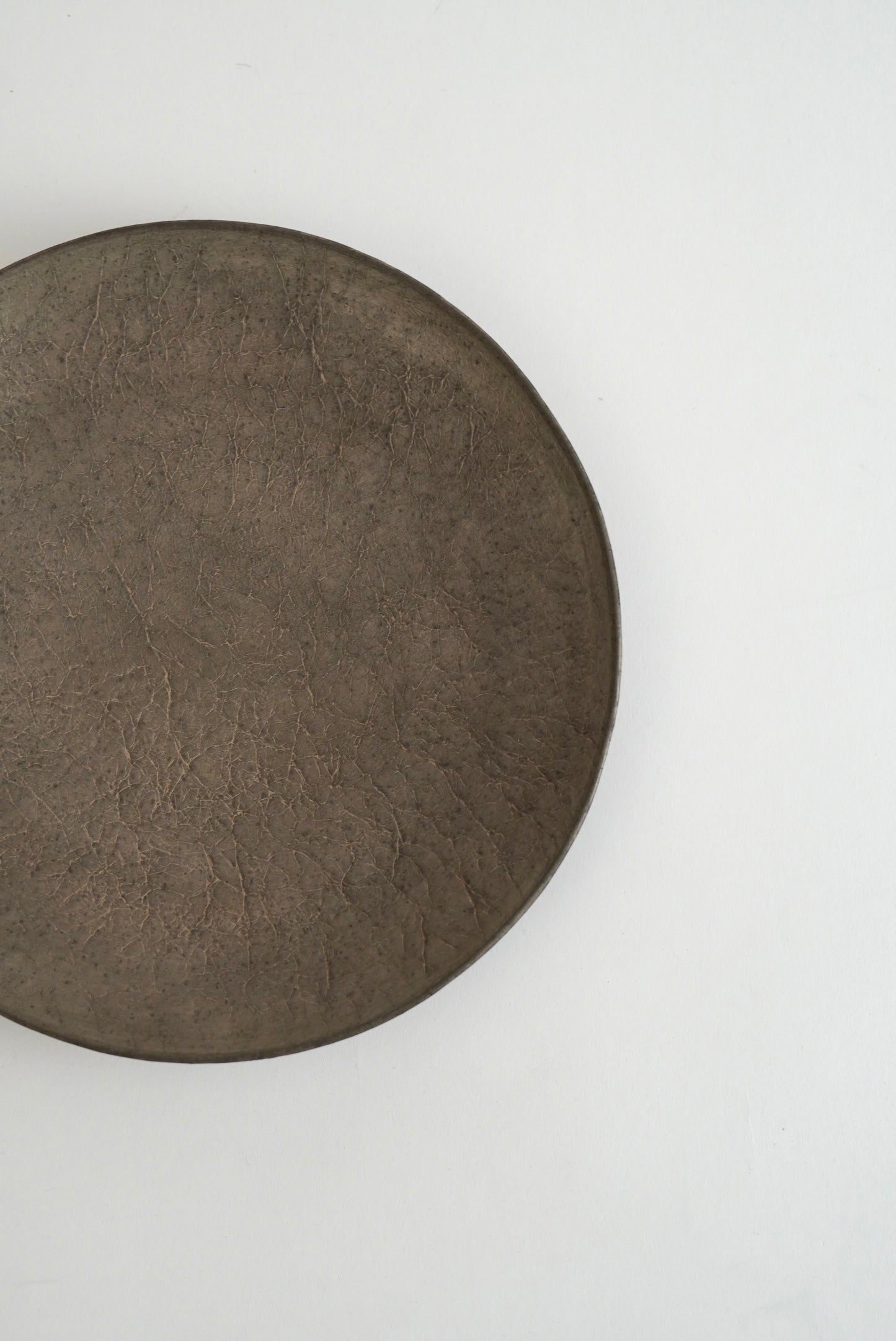 A round, dark brown textured plate or tray photographed from above on a plain white background.