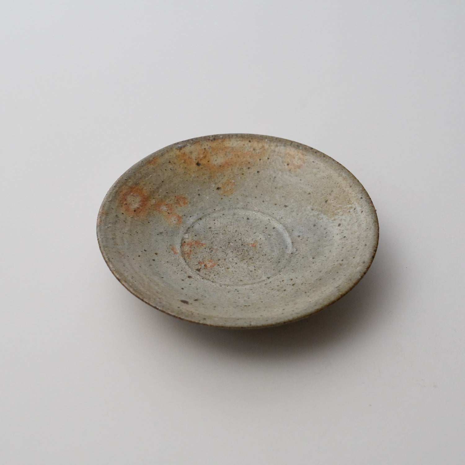 A gray and brown ceramic plate with a simple design, displayed against a white background.