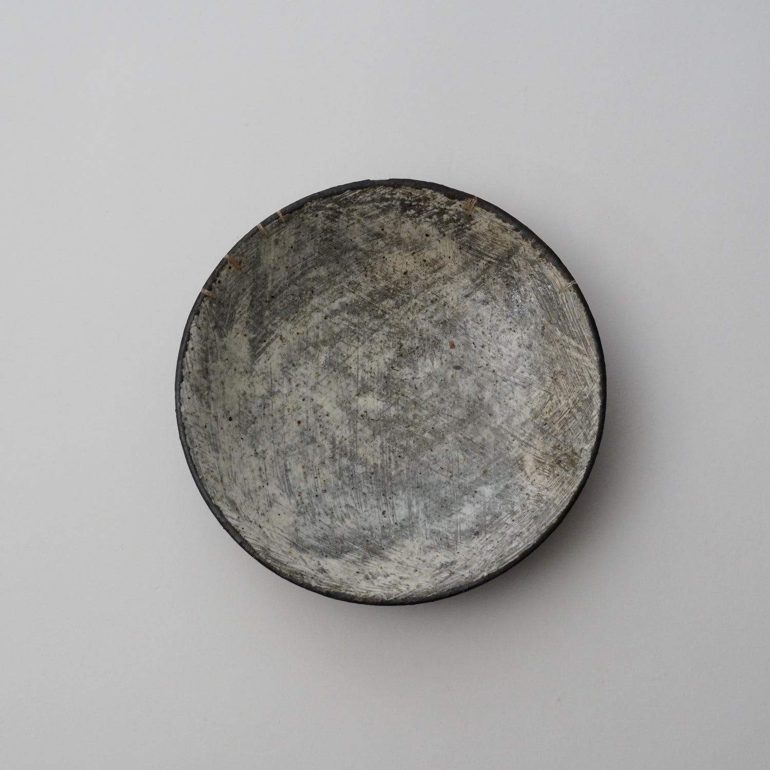 A black ceramic plate with a mottled, textured finish displayed on a neutral background.
