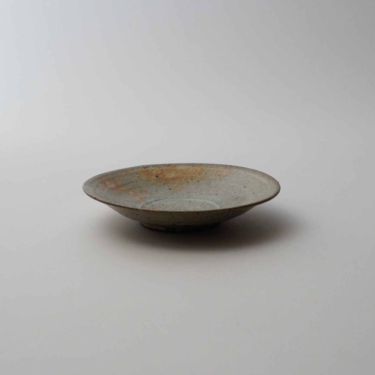 Metallic plate on a plain background. Handmade ceramic  plate by Japanese artist at Gallery tete Hong Kong.