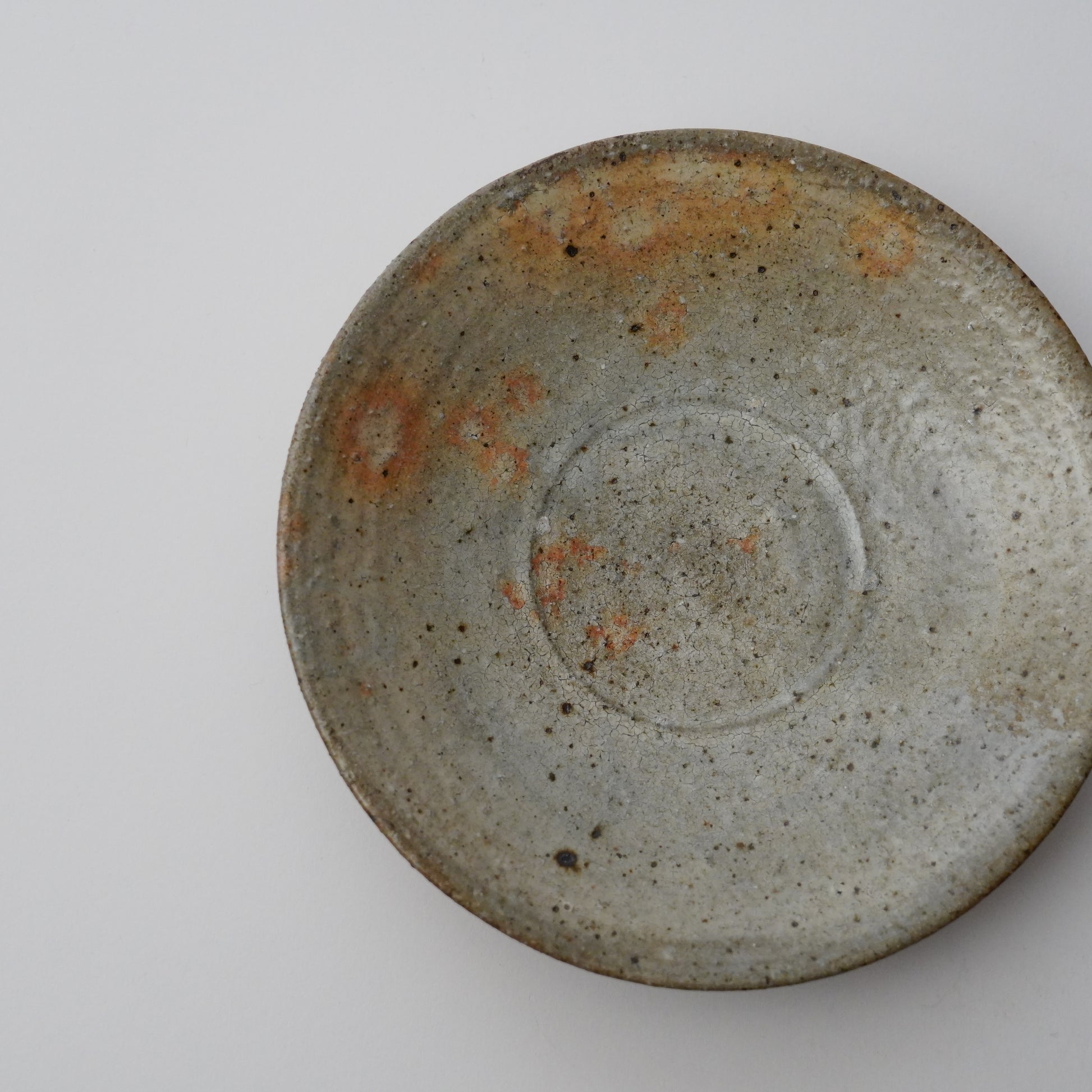 Ceramic plate with a rough texture on a white background. Handmade ceramic  plate by Japanese artist at Gallery tete Hong Kong.