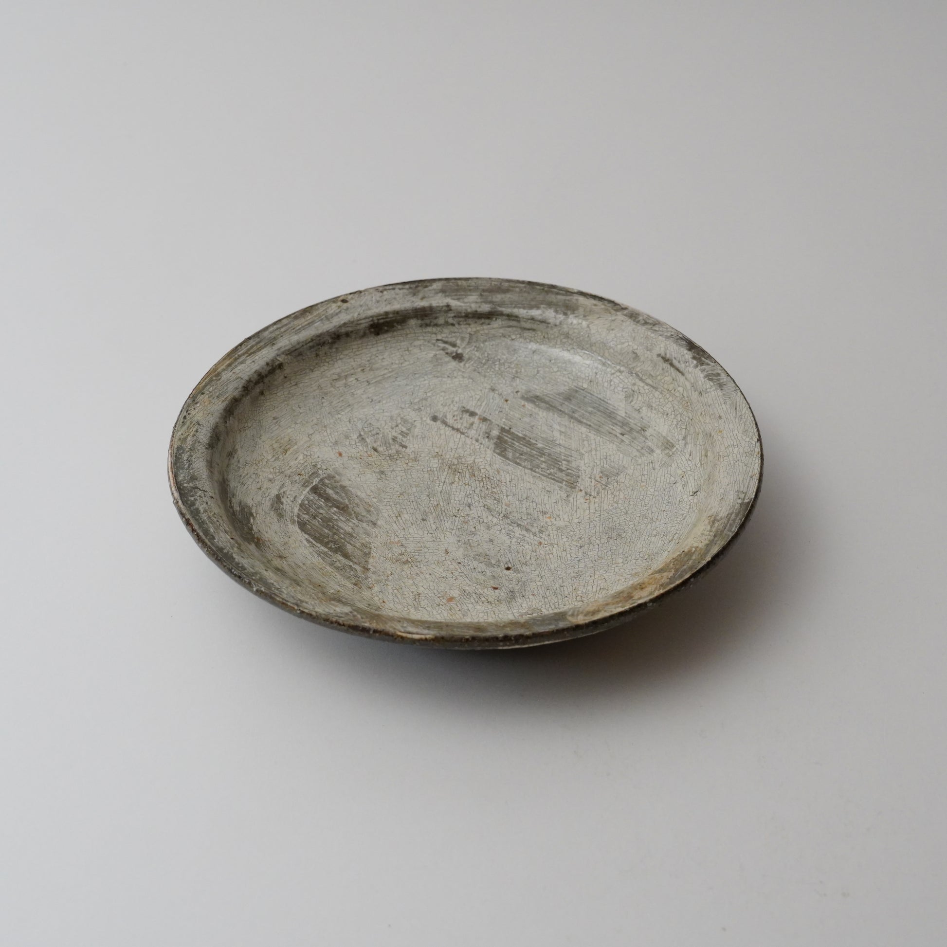 A gray ceramic plate with a simple design, displayed against a white background.