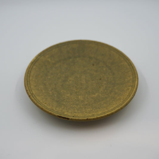 Round ceramic plate with a textured surface on a white background