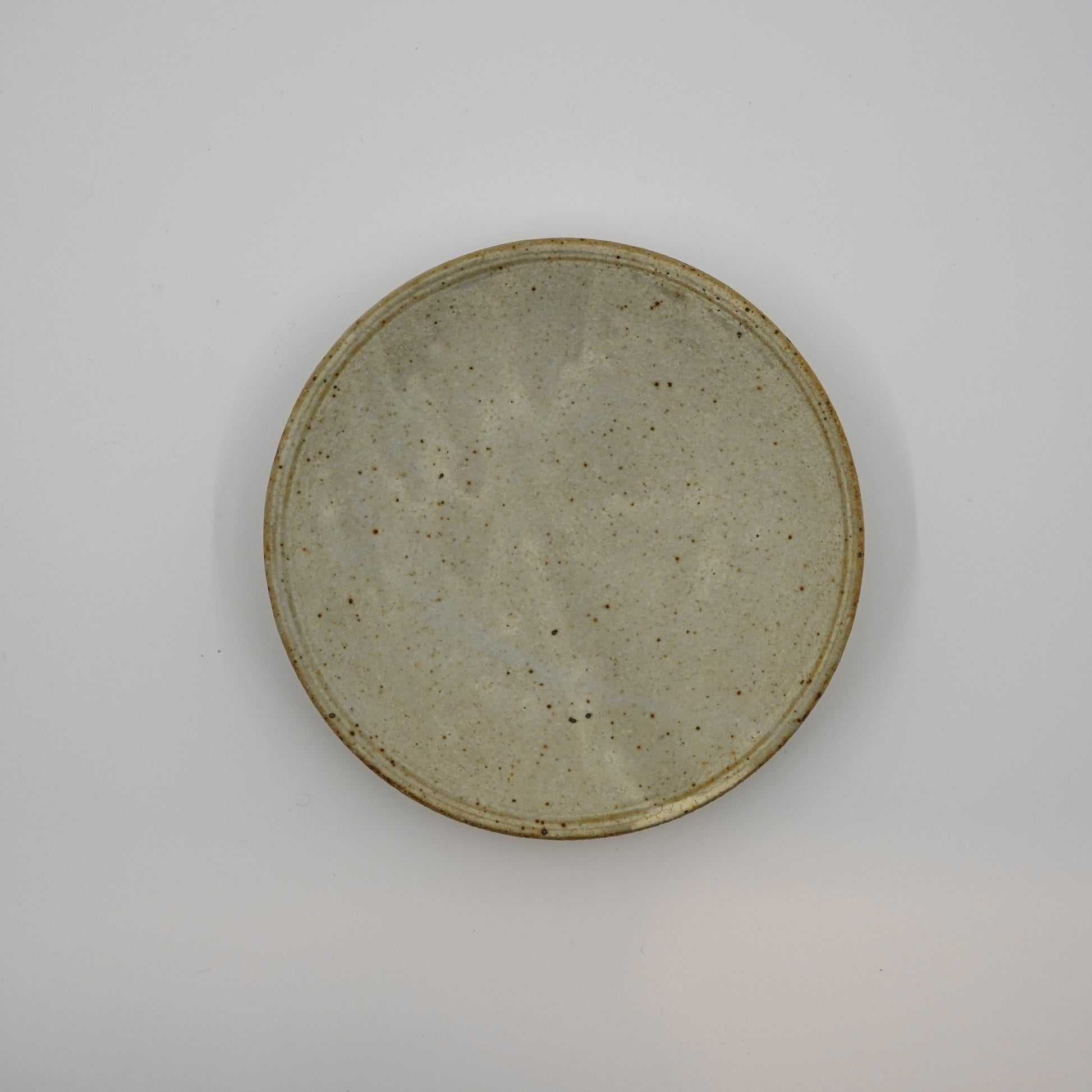 Round ceramic plate with a textured surface on a gray background