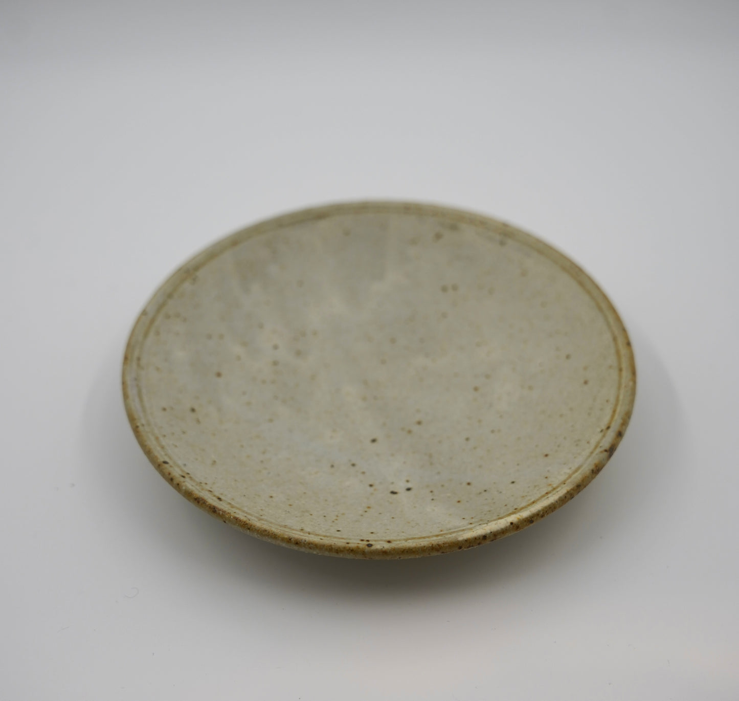 Round ceramic plate with a textured surface on a white background