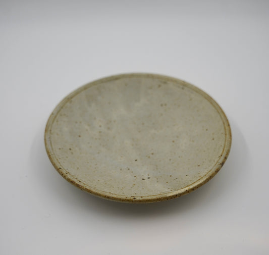 Round ceramic plate with a textured surface on a white background