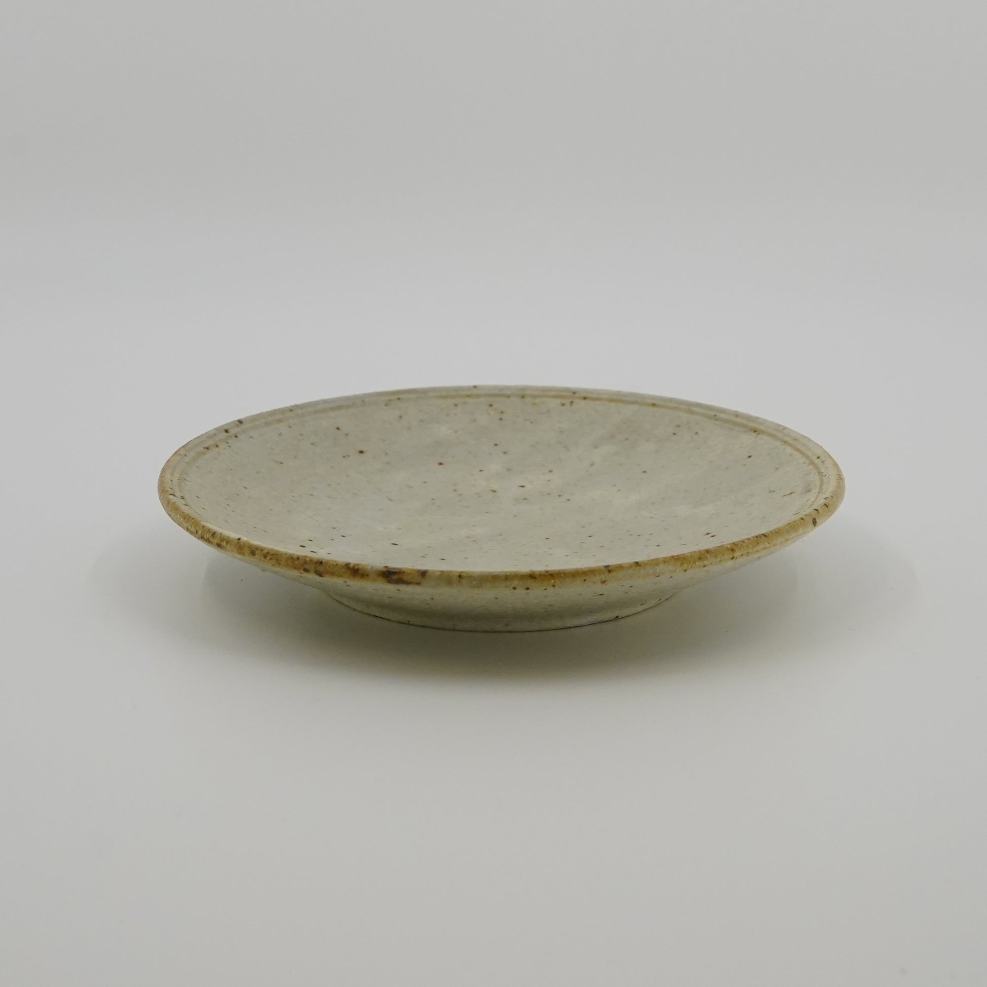 Ceramic plate with a speckled glaze on a white background