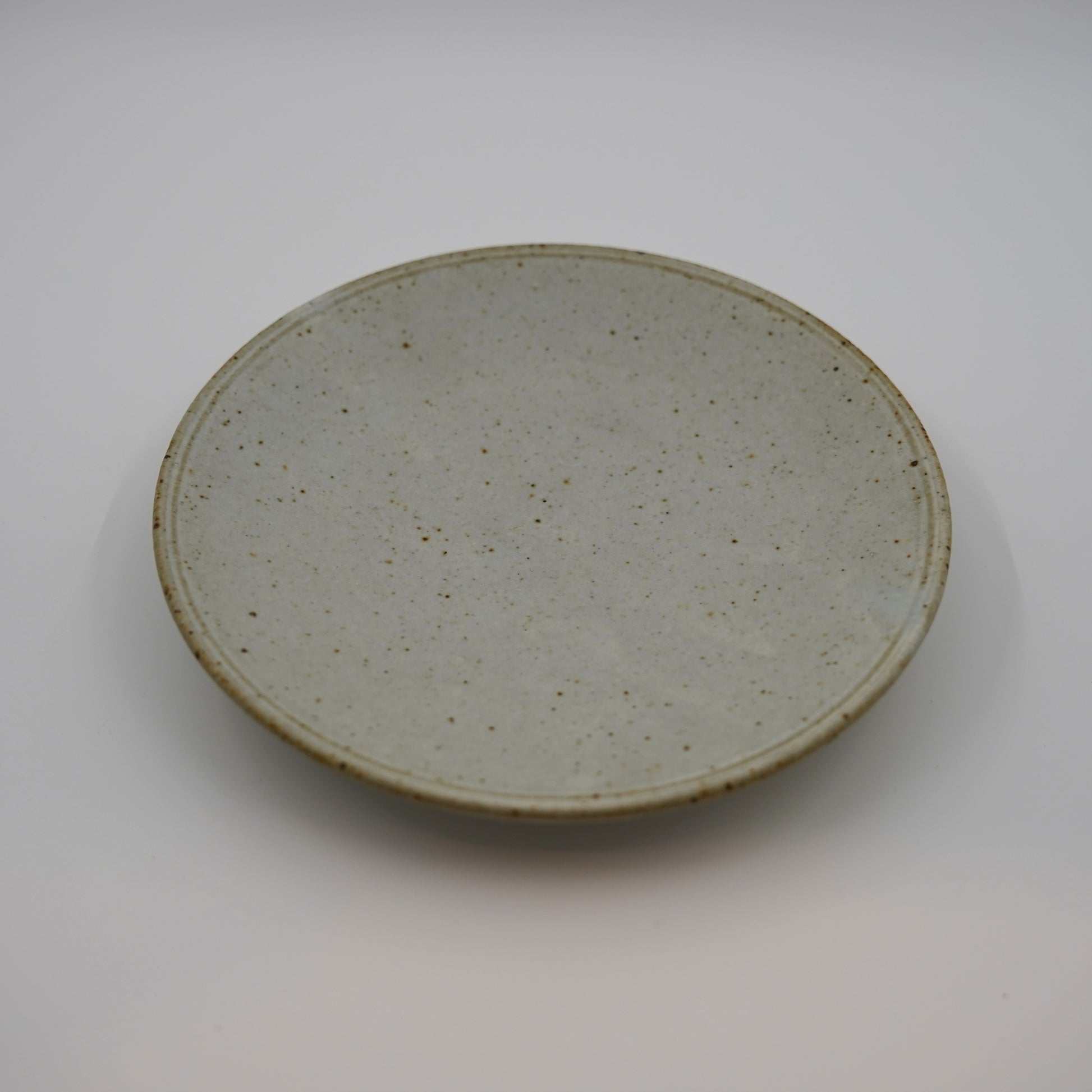 Round ceramic plate with a textured surface on a white background