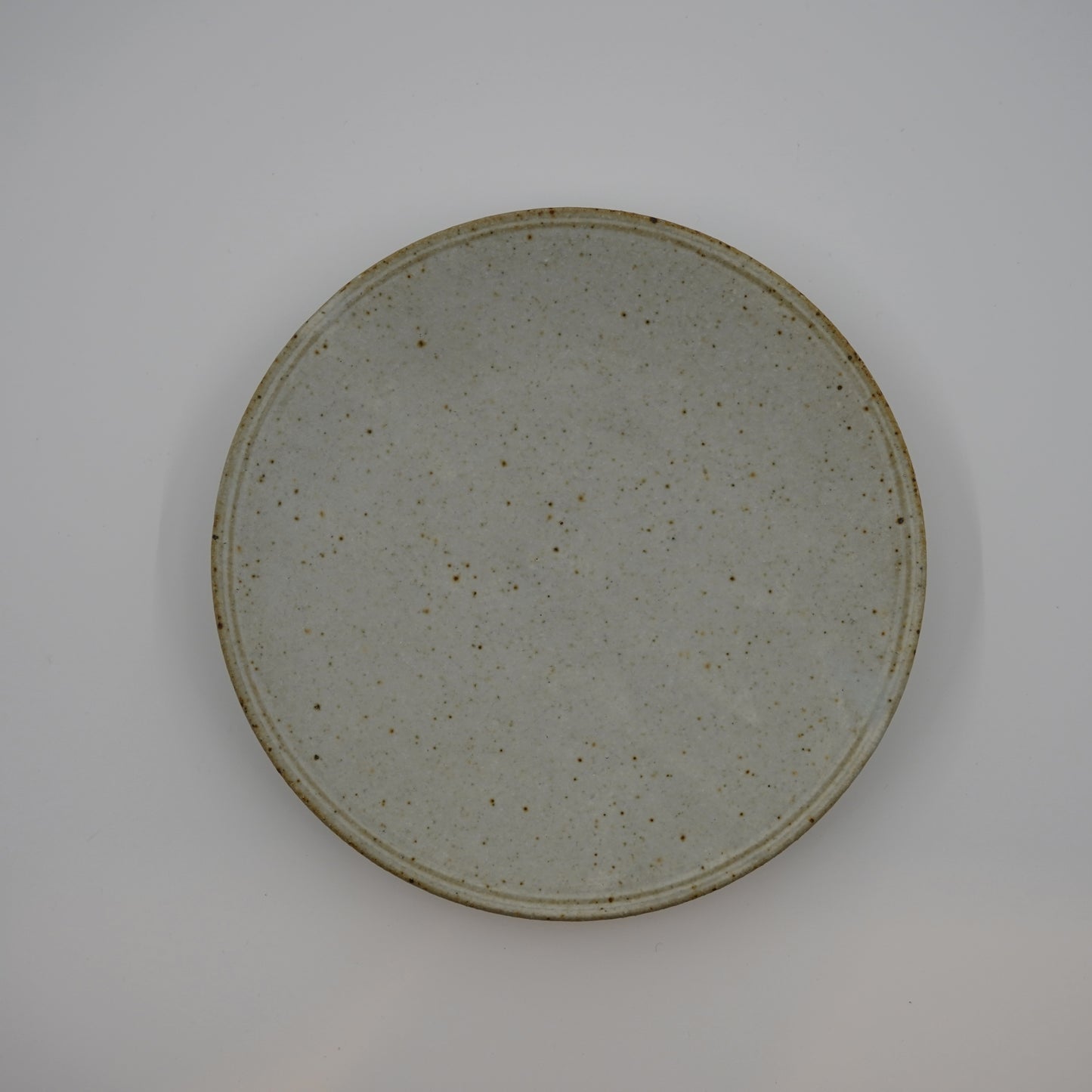 Round ceramic plate with a textured surface on a plain background