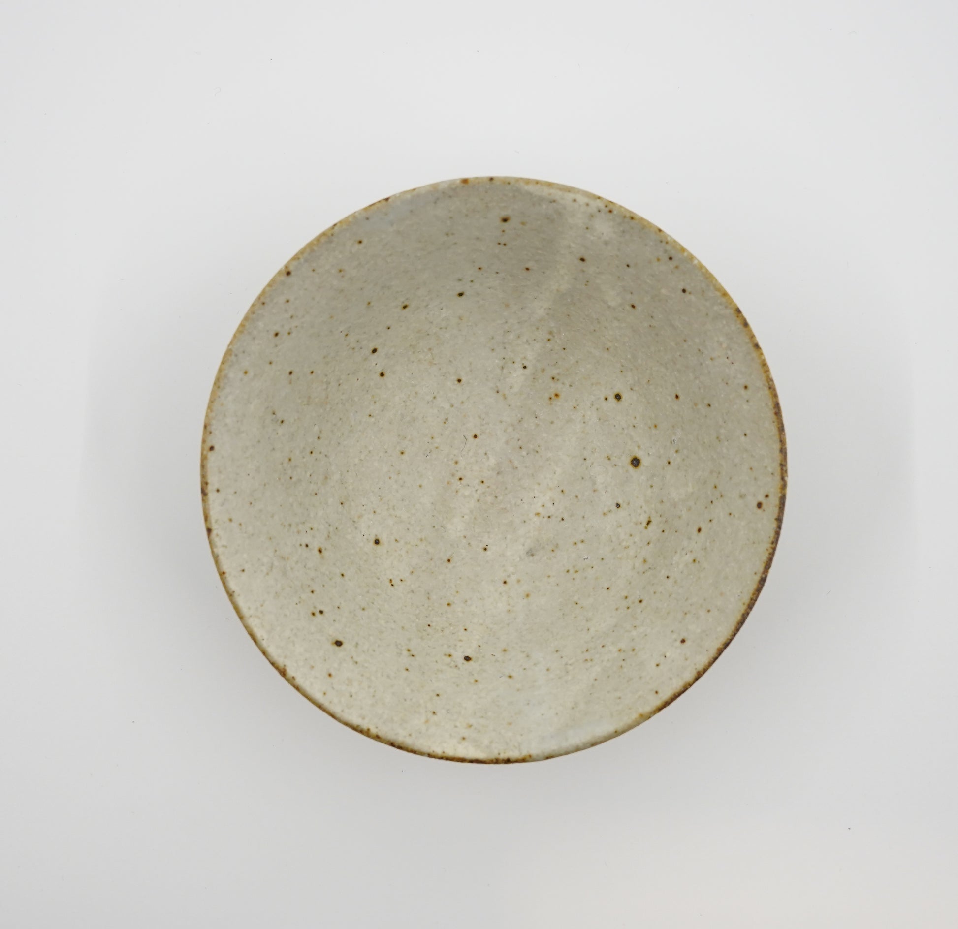 Round ceramic plate with a speckled texture on a white background