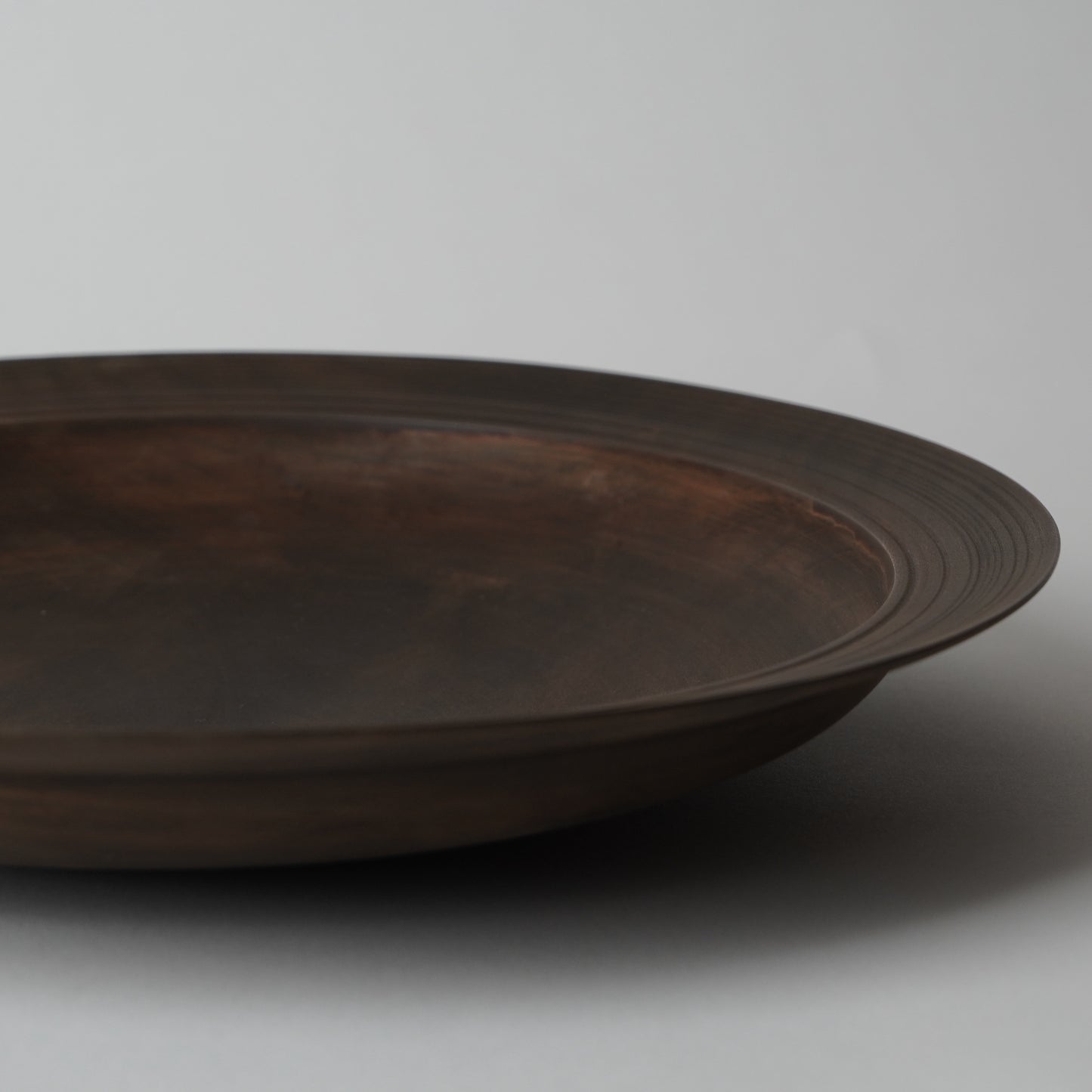 Dark brown ceramic plate on a light gray background
