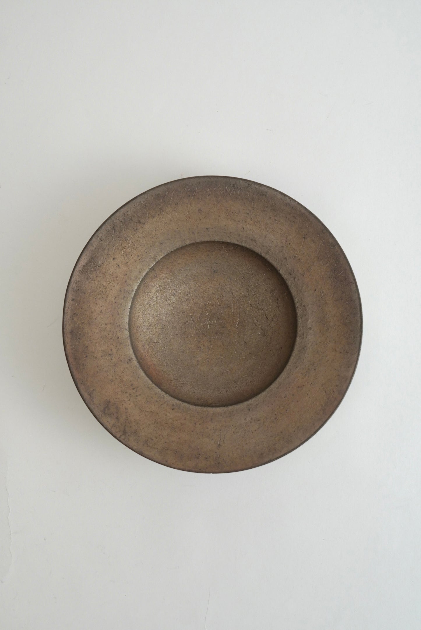 A round, shallow ceramic plate or bowl with a wide rim, shown from a top-down perspective on a plain white background.
