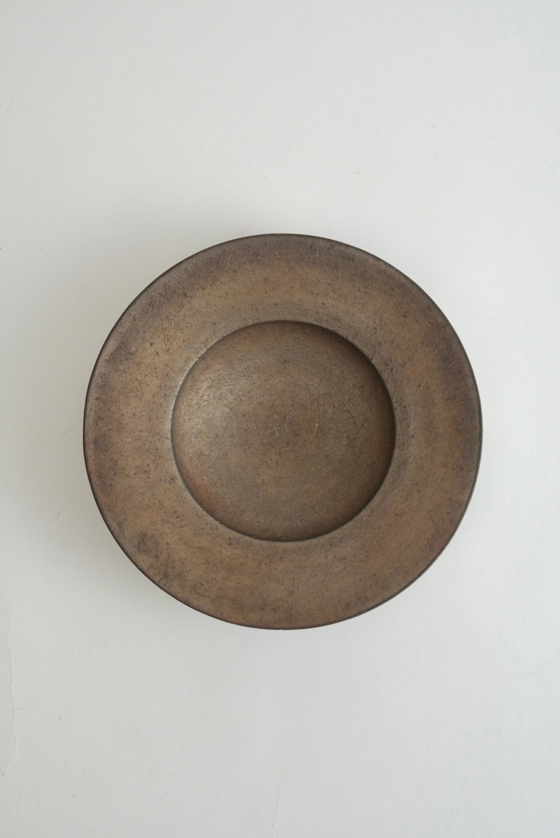 A round, shallow ceramic plate or bowl with a wide rim, shown from a top-down perspective on a plain white background.
