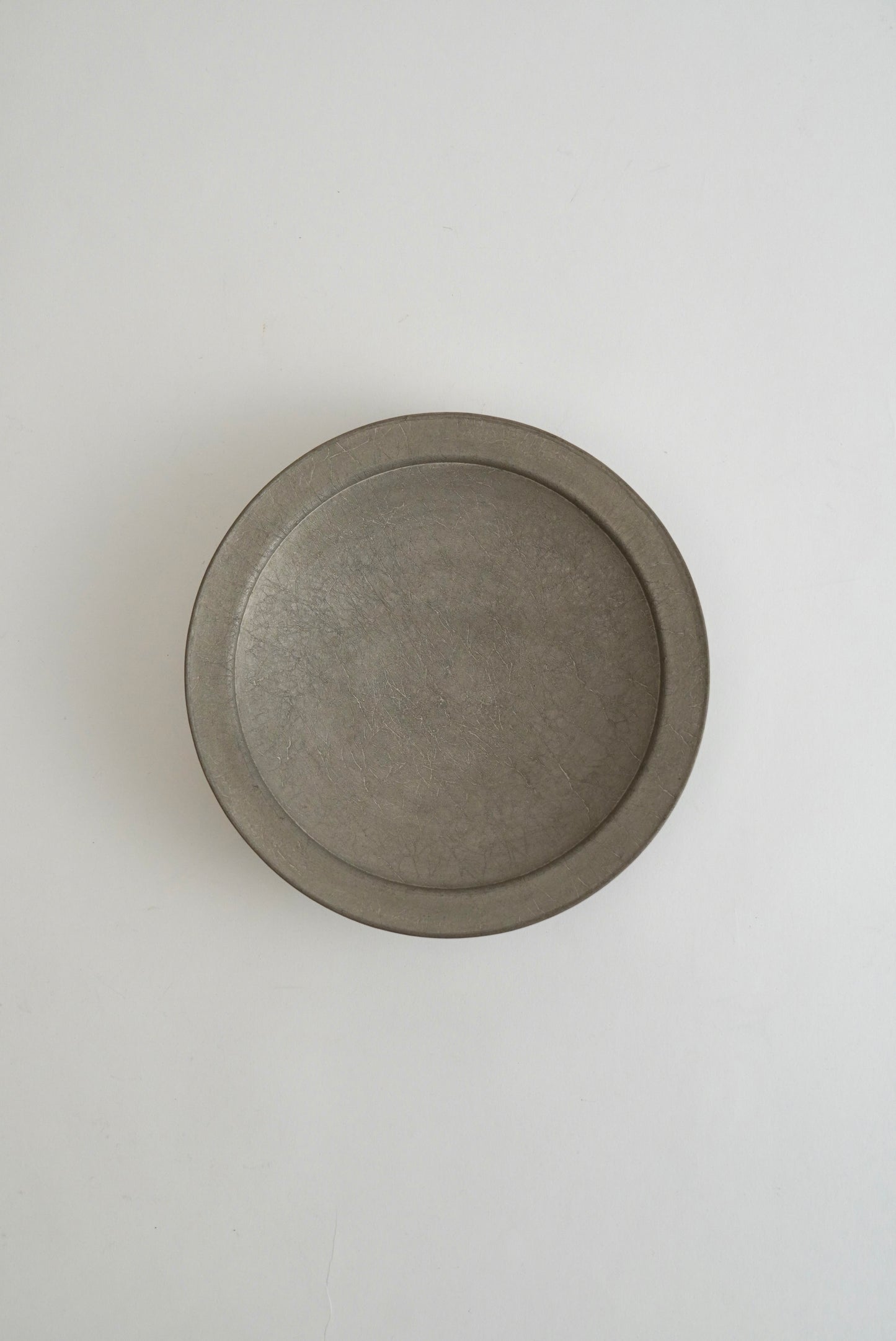A round, shallow gray ceramic dish or plate with a matte, textured finish, photographed from directly above on a clean white background.