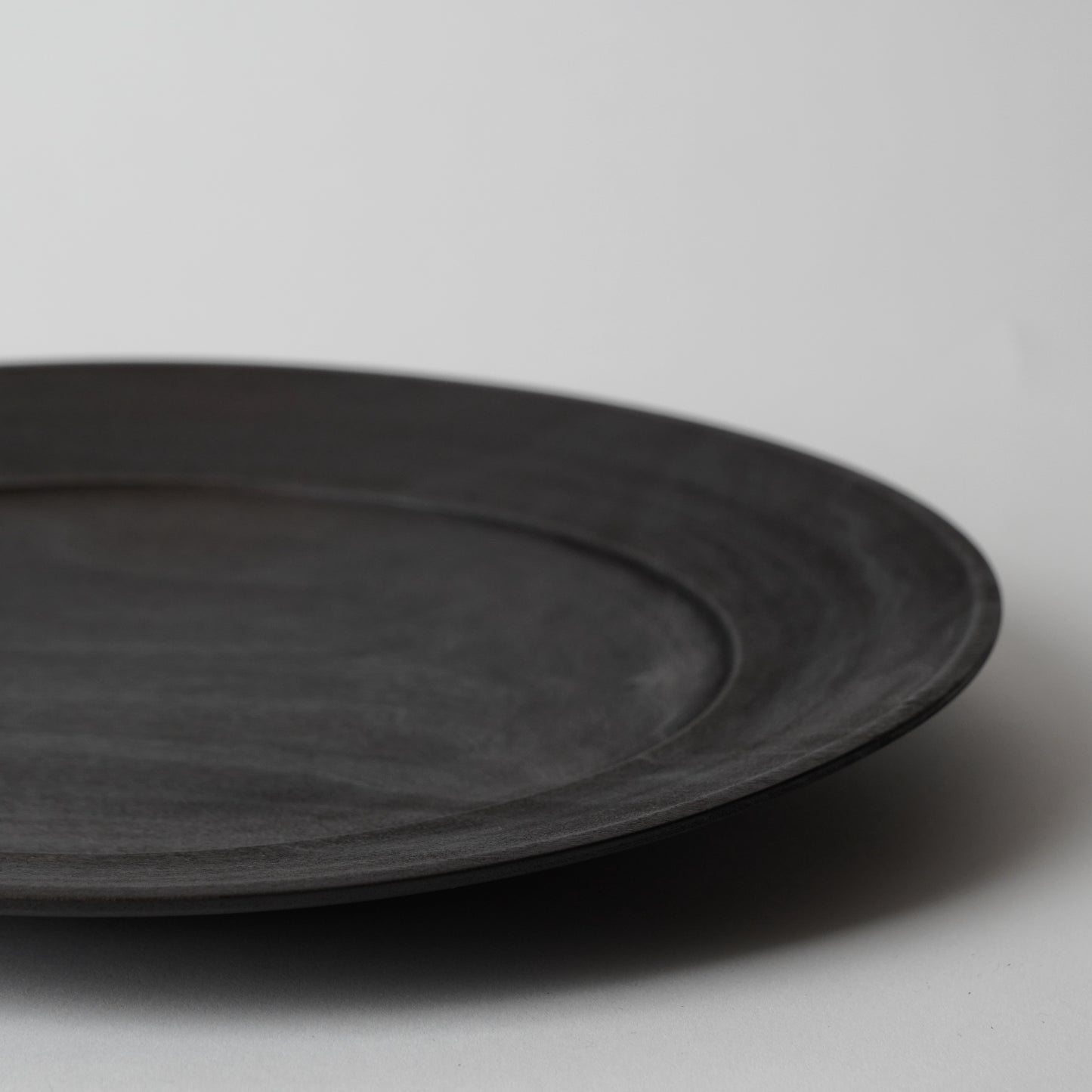 Black wooden plate on a light gray background