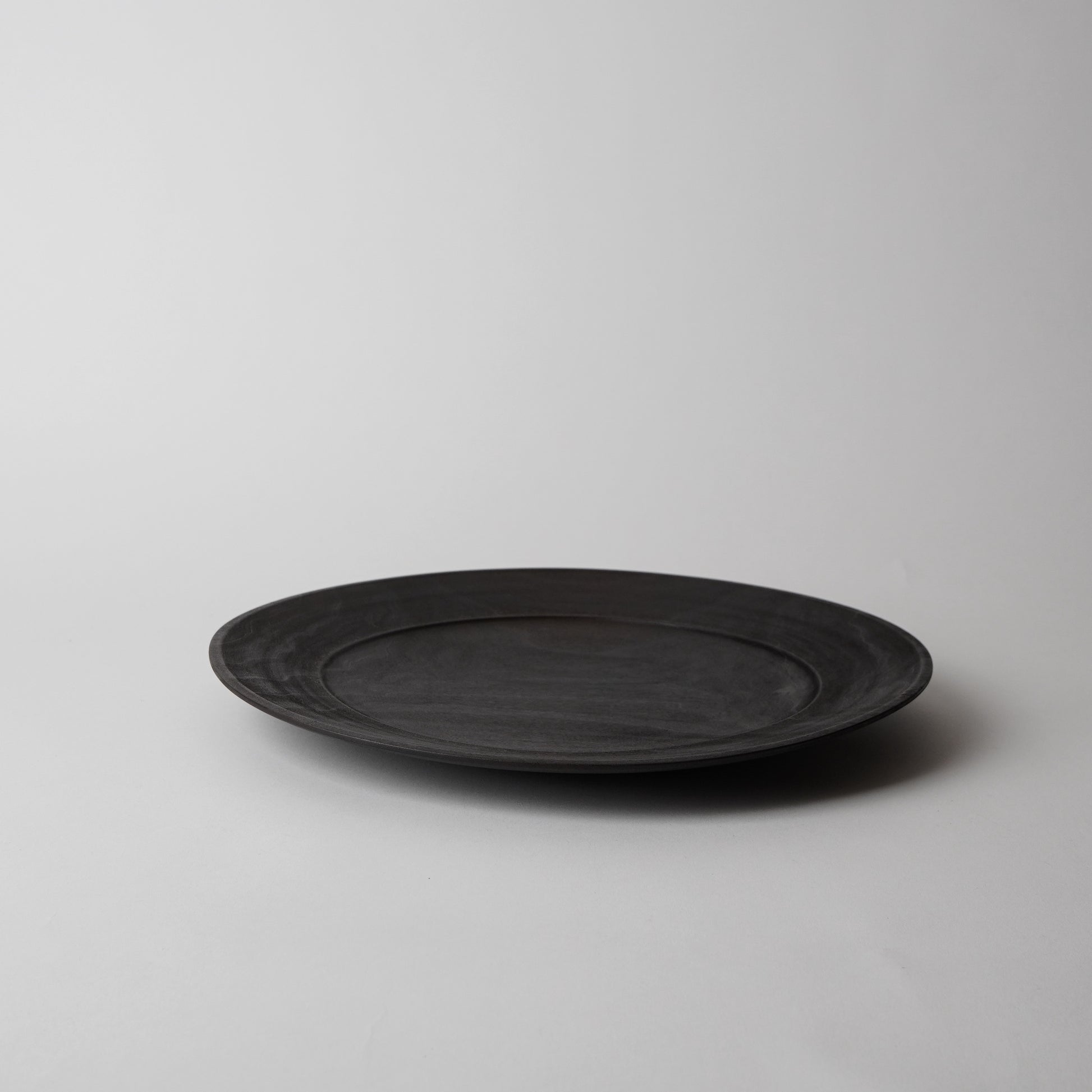 Black wooden plate on a light gray background